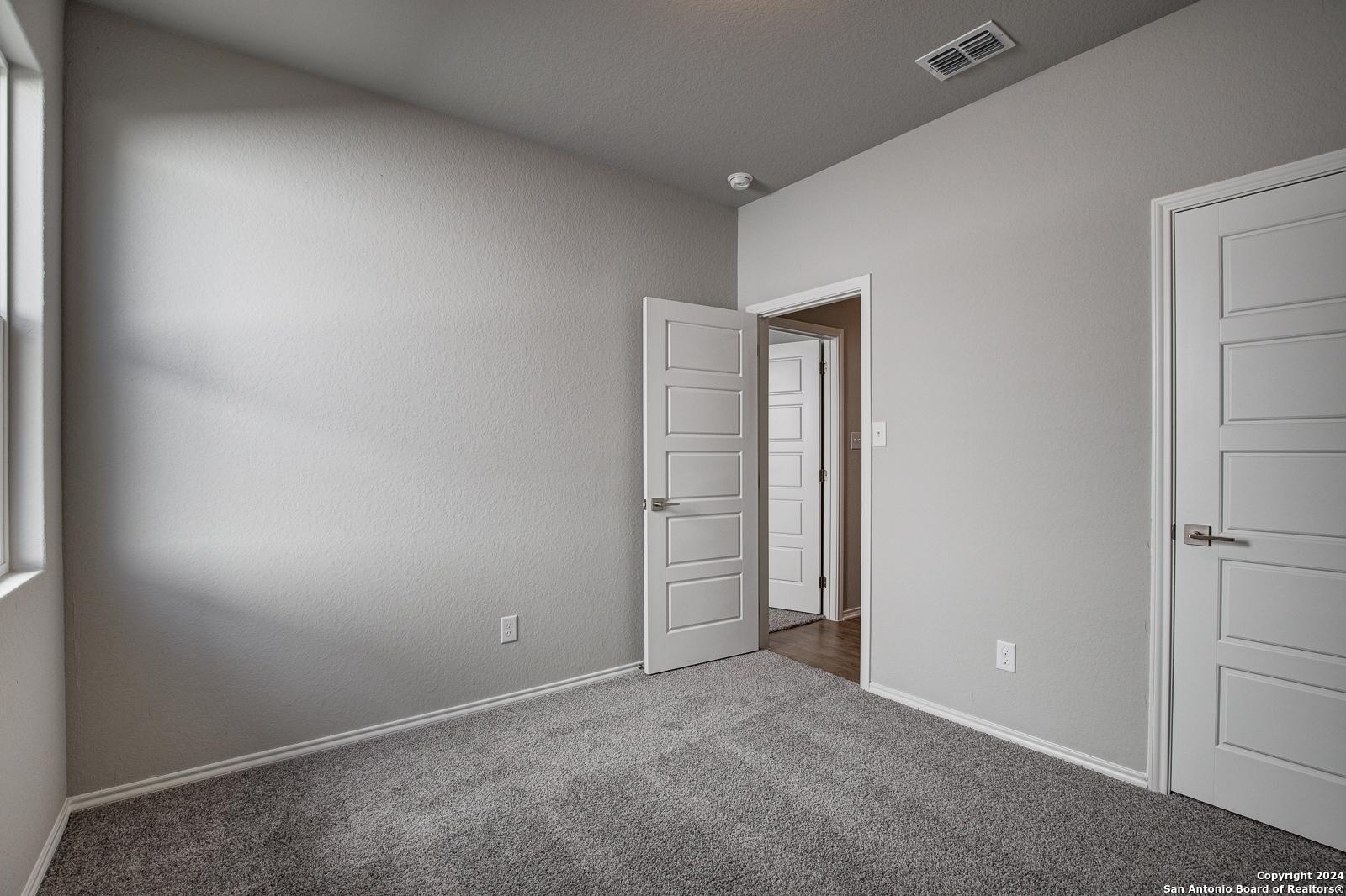 Spacious secondary bedroom with gray walls, carpet flooring, and en-suite door in Davidson Homes The Frio B, San Antonio