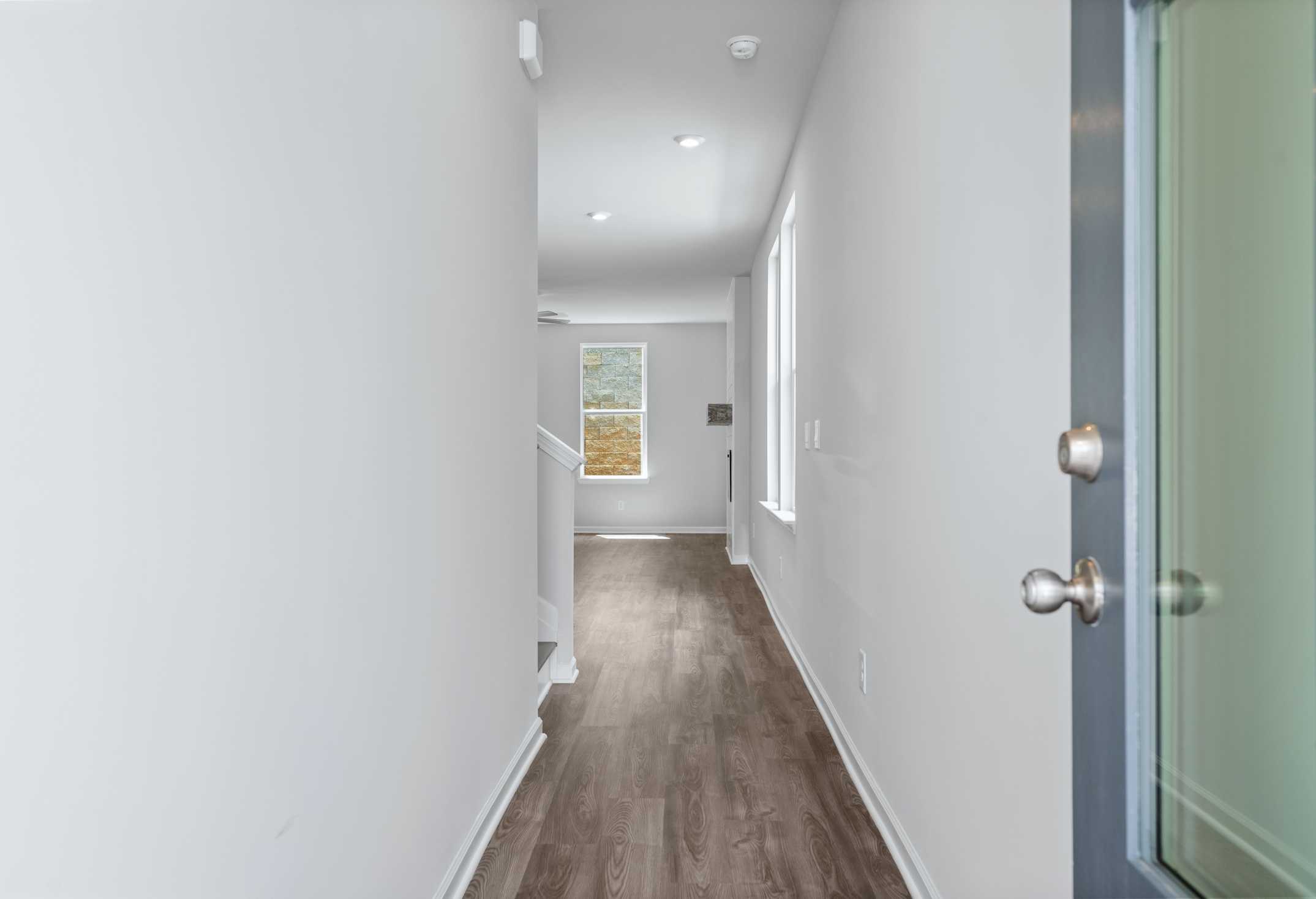 Spacious hallway in The Cary A 2-story home featuring light wood floors, white walls, ascending staircase, and window to upper master suite