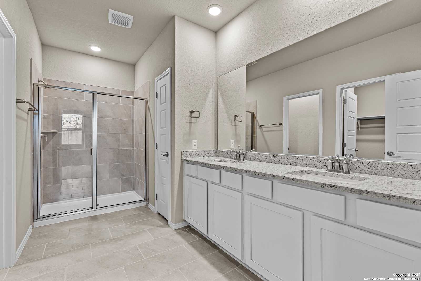 Modern master bathroom featuring double vanity, quartz countertop, and frameless glass shower in Davidson Homes The Douglas F, San Antonio