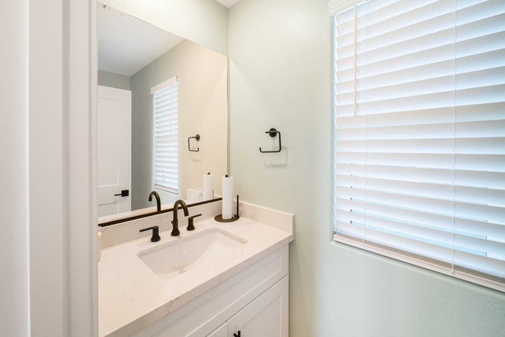 Spacious master bathroom in The Wilmington with modern white vanity, quartz sink, bronze faucet, and soft green walls