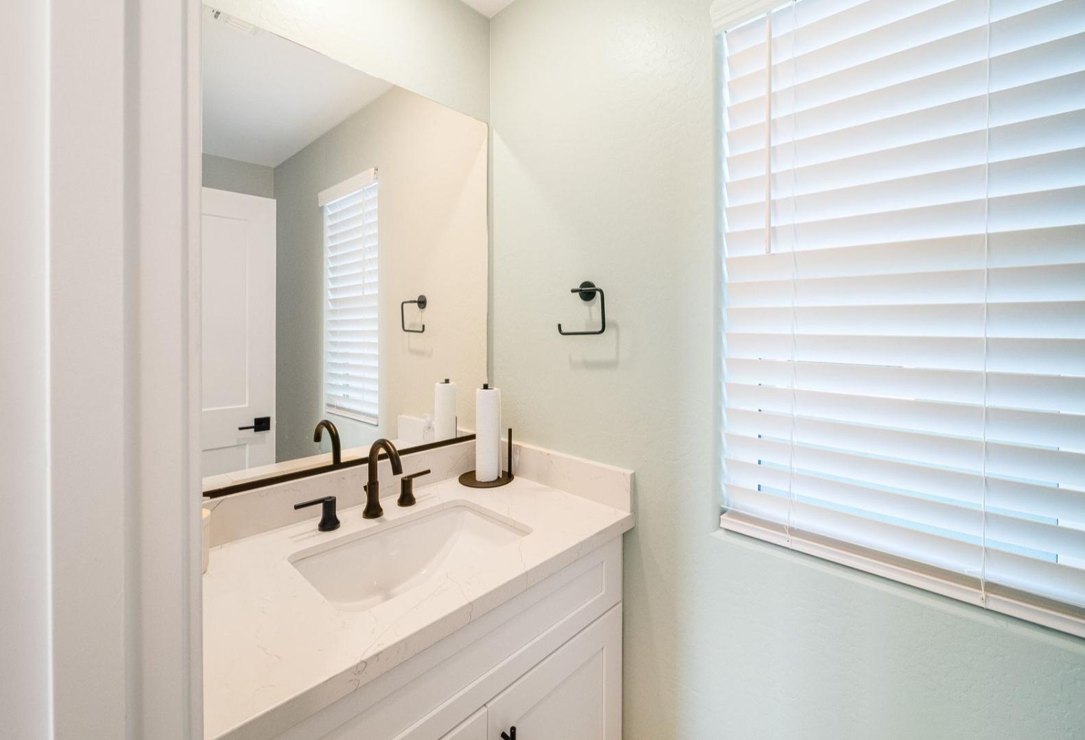 Spacious master bathroom in The Wilmington with white quartz vanity, bronze faucet, large mirror, and soft green walls