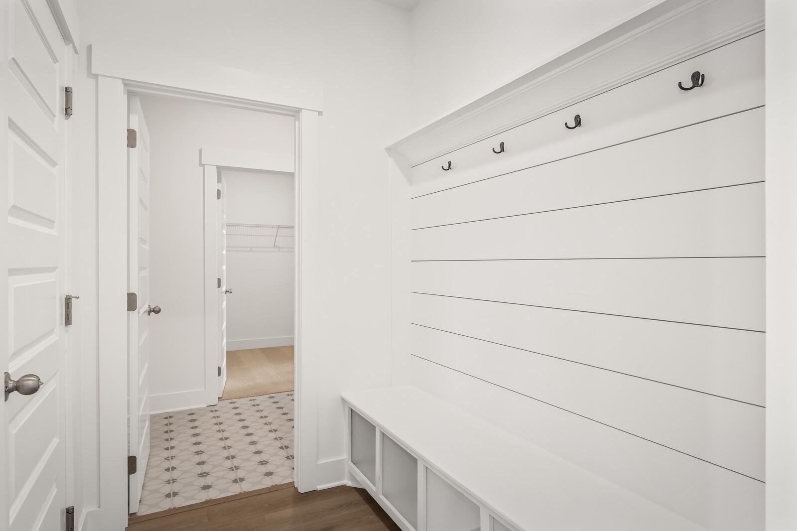 White shiplap mudroom with built-in bench, coat hooks, and walk-in closet access in Davidson Homes The Ash A, Gallatin, Tennessee