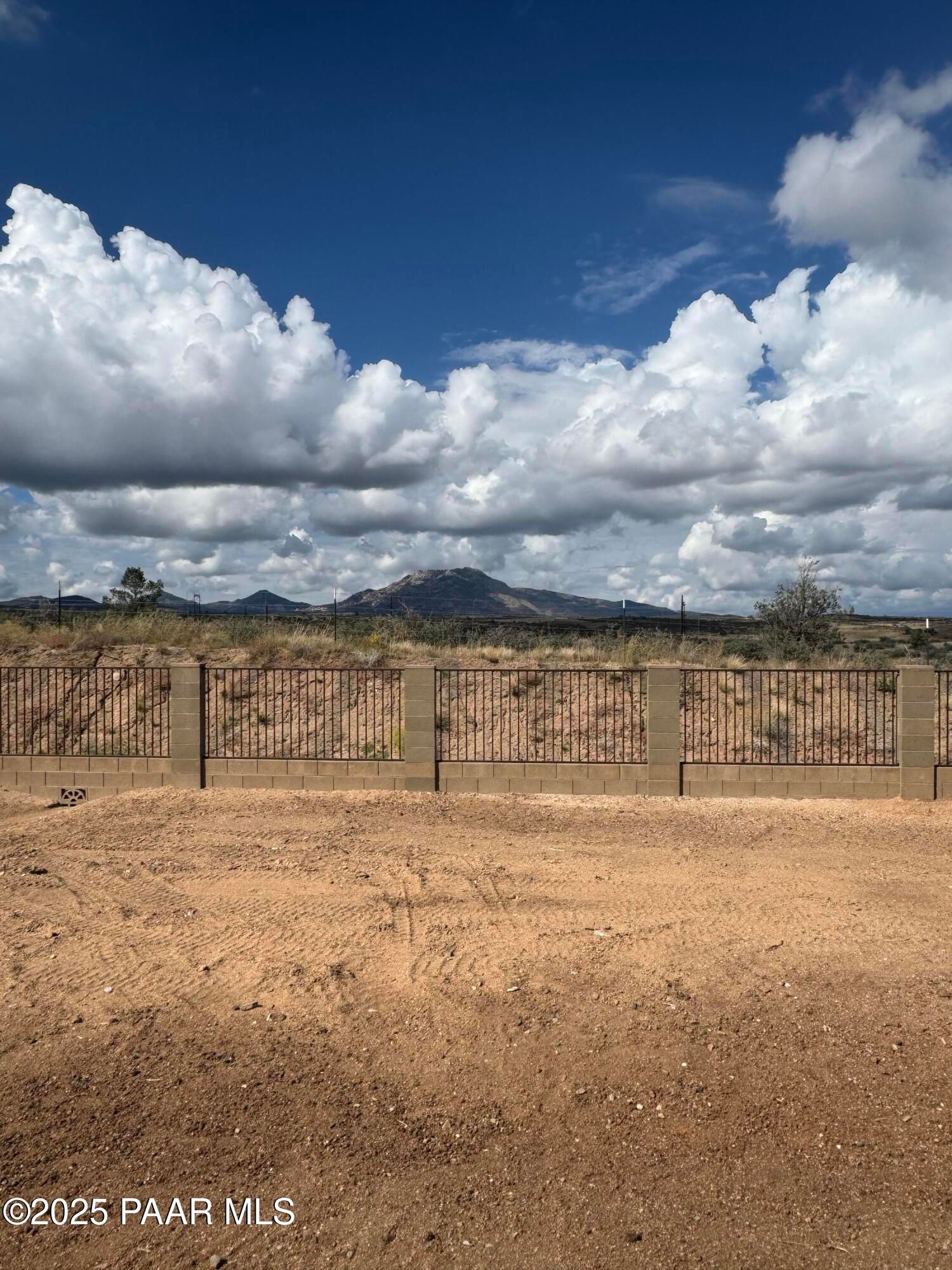 Scenic mountain vista with blue skies and fluffy clouds over fenced desert lot for Davidson Homes The Monarch E in Westwood, Prescott, Arizona
