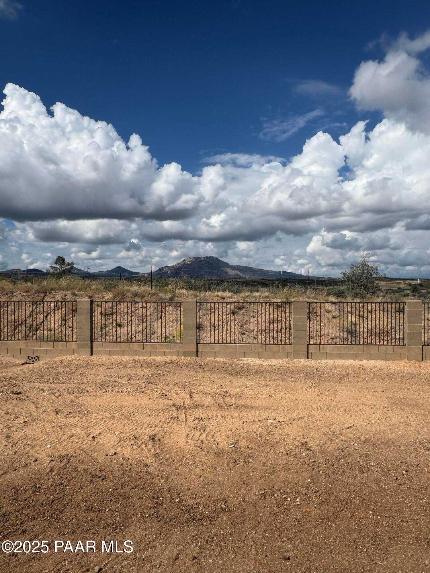 Scenic mountain vista with blue skies and fluffy clouds over fenced desert lot for Davidson Homes The Monarch E in Westwood, Prescott, Arizona