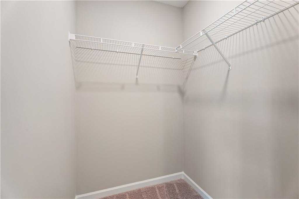 Spacious walk-in closet with white wire shelving and beige walls in The Bartlett master suite, Davidson Homes, Phenix City, Alabama