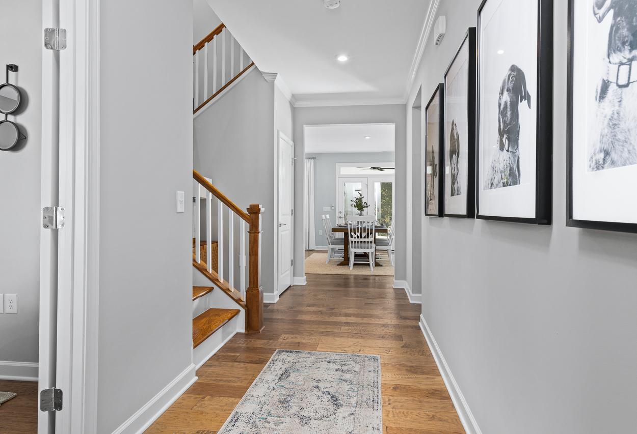Bright foyer and hallway in The Hemlock A featuring hardwood floors, a wooden staircase, and view of the dining area.