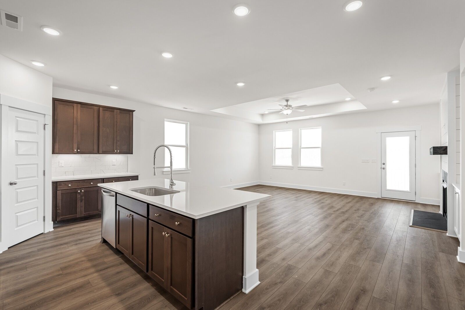 Open-concept kitchen with dark wood cabinets, white island, and luxury vinyl plank flooring in Davidson Homes Cottonwood E, Gallatin TN