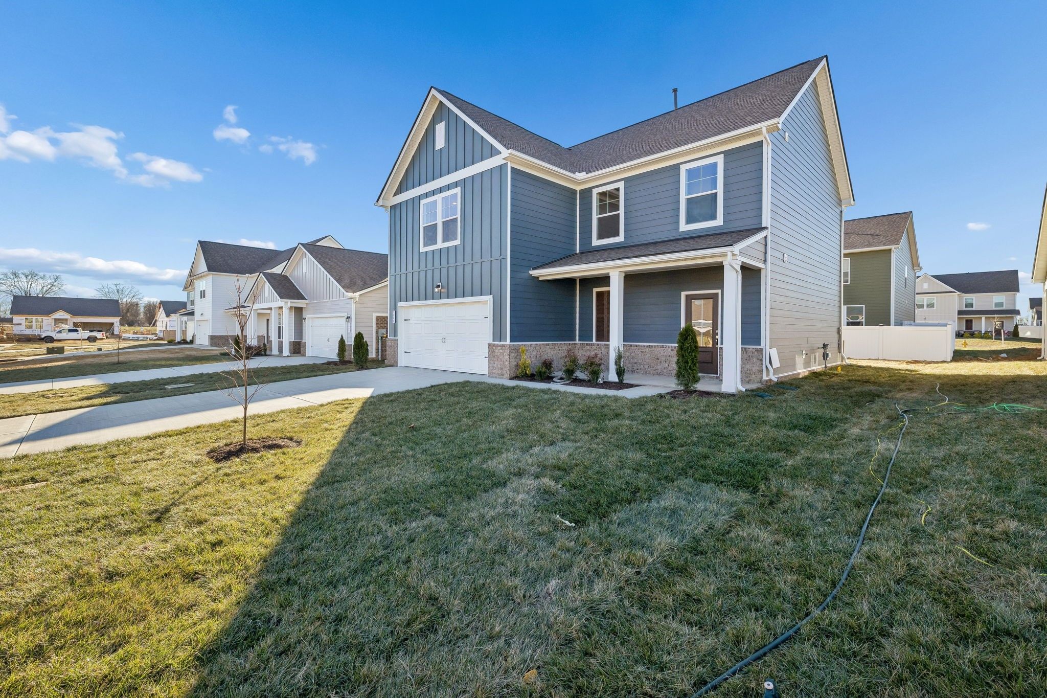 Gray two-story home with 2-car garage, front porch, and shingled roof in Sage Farms, White House, Tennessee - Davidson Homes The Gordon B