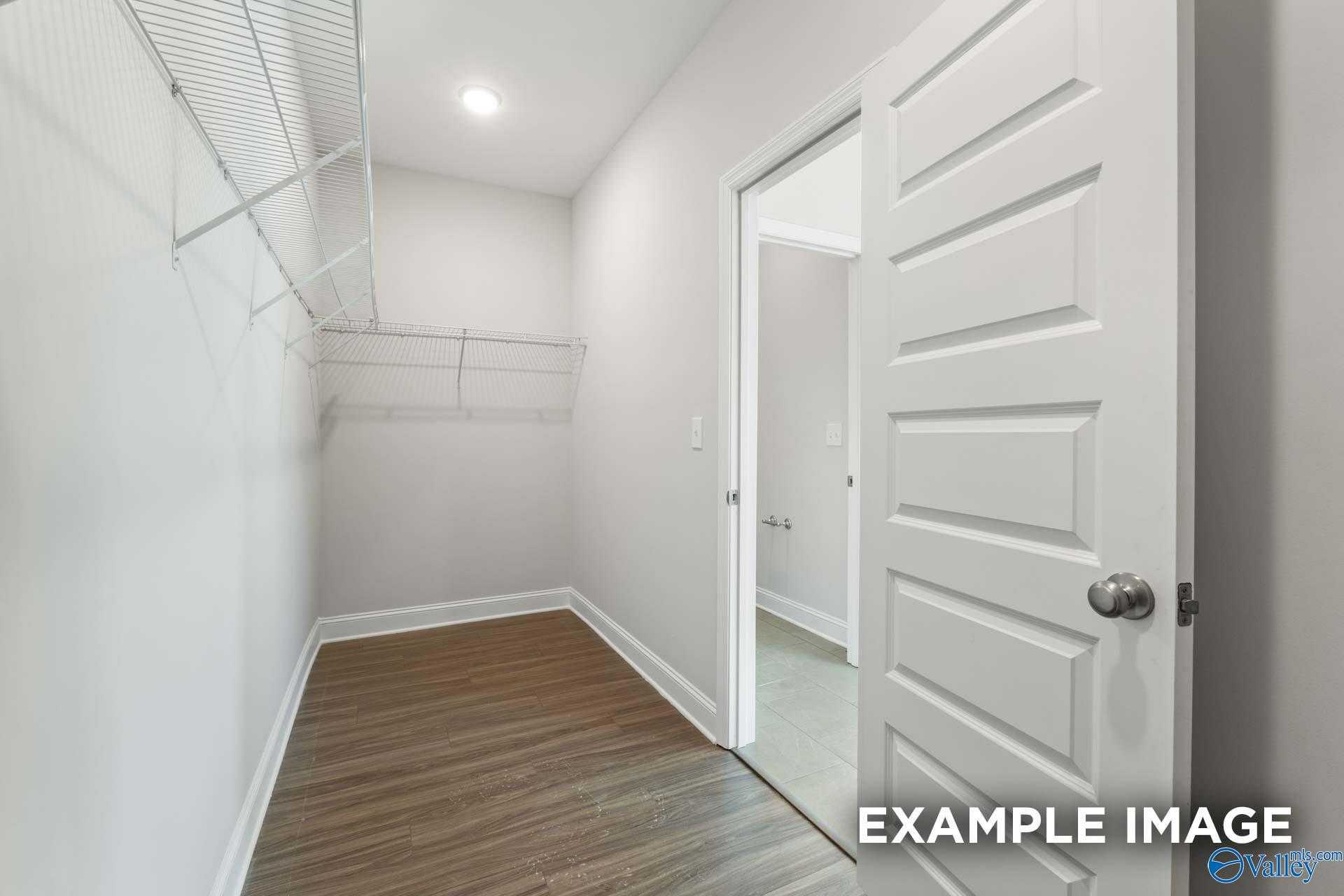 Spacious walk-in closet with wire shelving, neutral walls, hardwood floors in master suite of Davidson Homes The Montgomery, Athens, AL