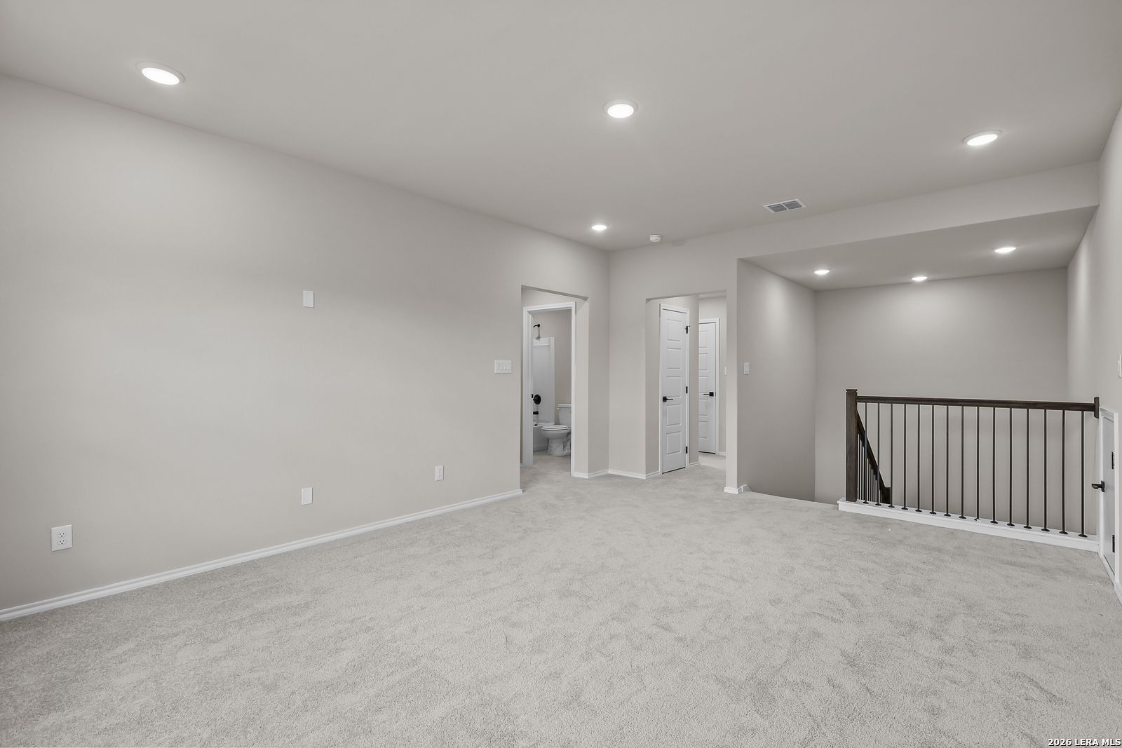 Spacious carpeted game room loft with wrought iron stair railing and recessed lighting in Davidson Homes Sequoia C, San Antonio