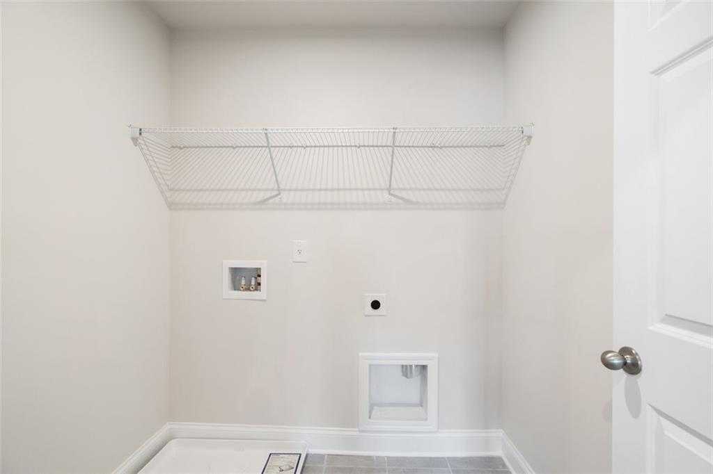 Bright laundry room with wire shelving and washer-dryer hookups in Davidson Homes The Willow B, Hoschton, Georgia