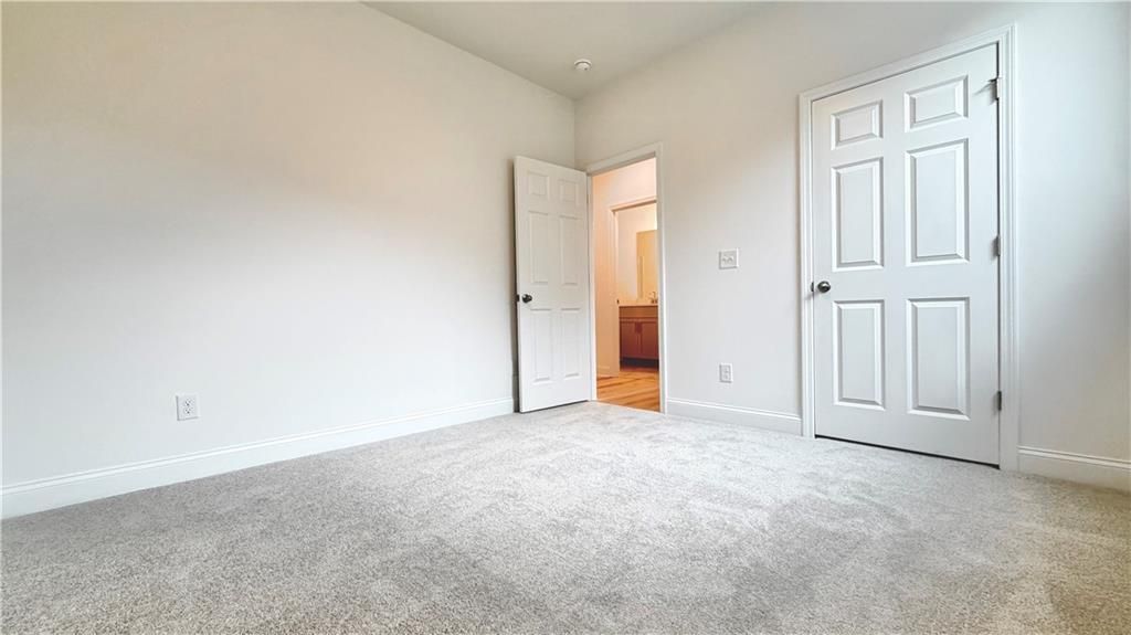 Bright bedroom with plush carpet and closet in The Glenwood A floor plan at Wehunt Meadows in Hoschton, Georgia.
