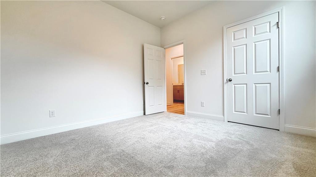 Bright bedroom with plush carpet and closet in The Glenwood A floor plan at Wehunt Meadows in Hoschton, Georgia.