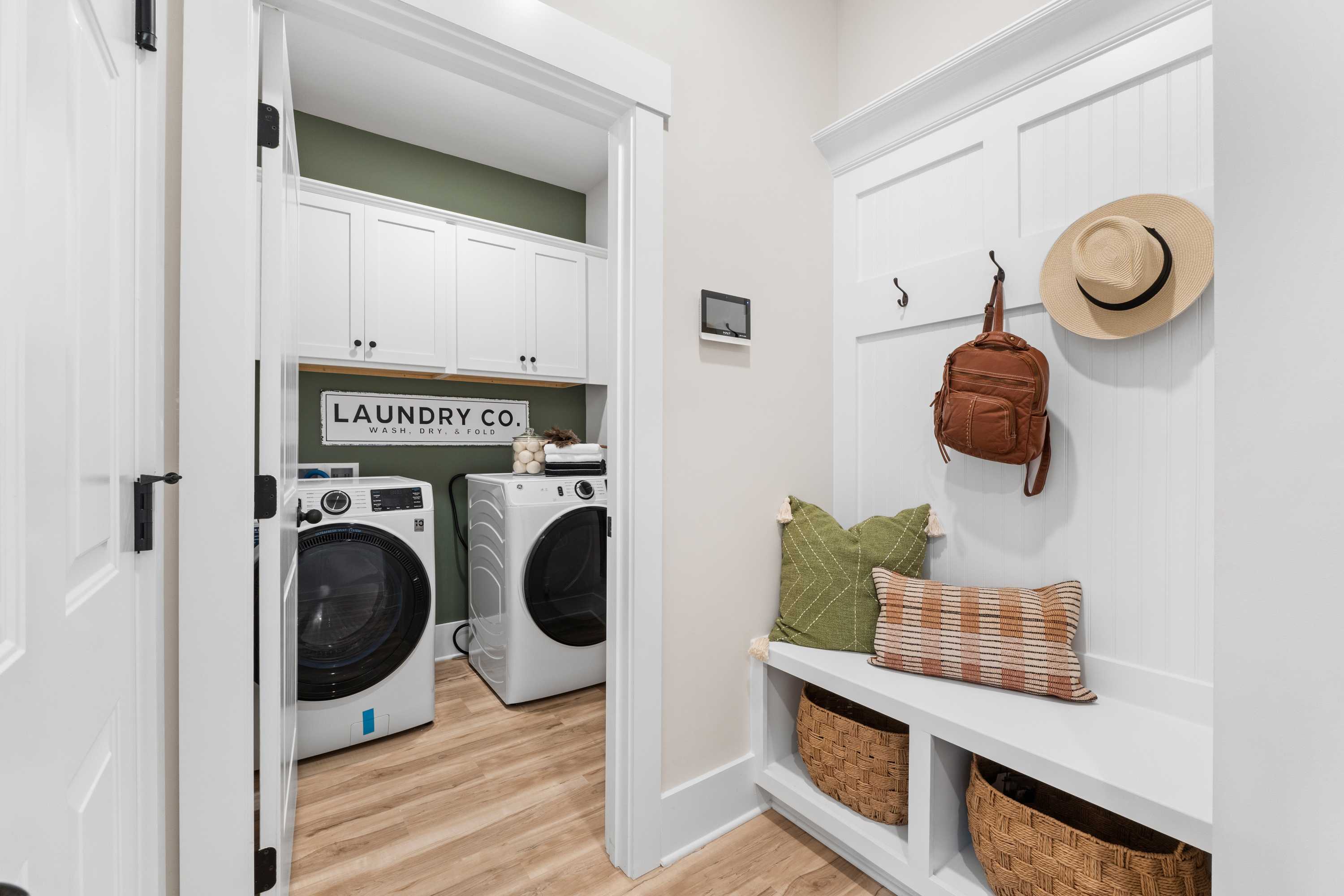 Modern laundry mudroom with washer dryer built-in cabinets cushioned bench wicker baskets wall hooks in Spragins Cove Huntsville AL