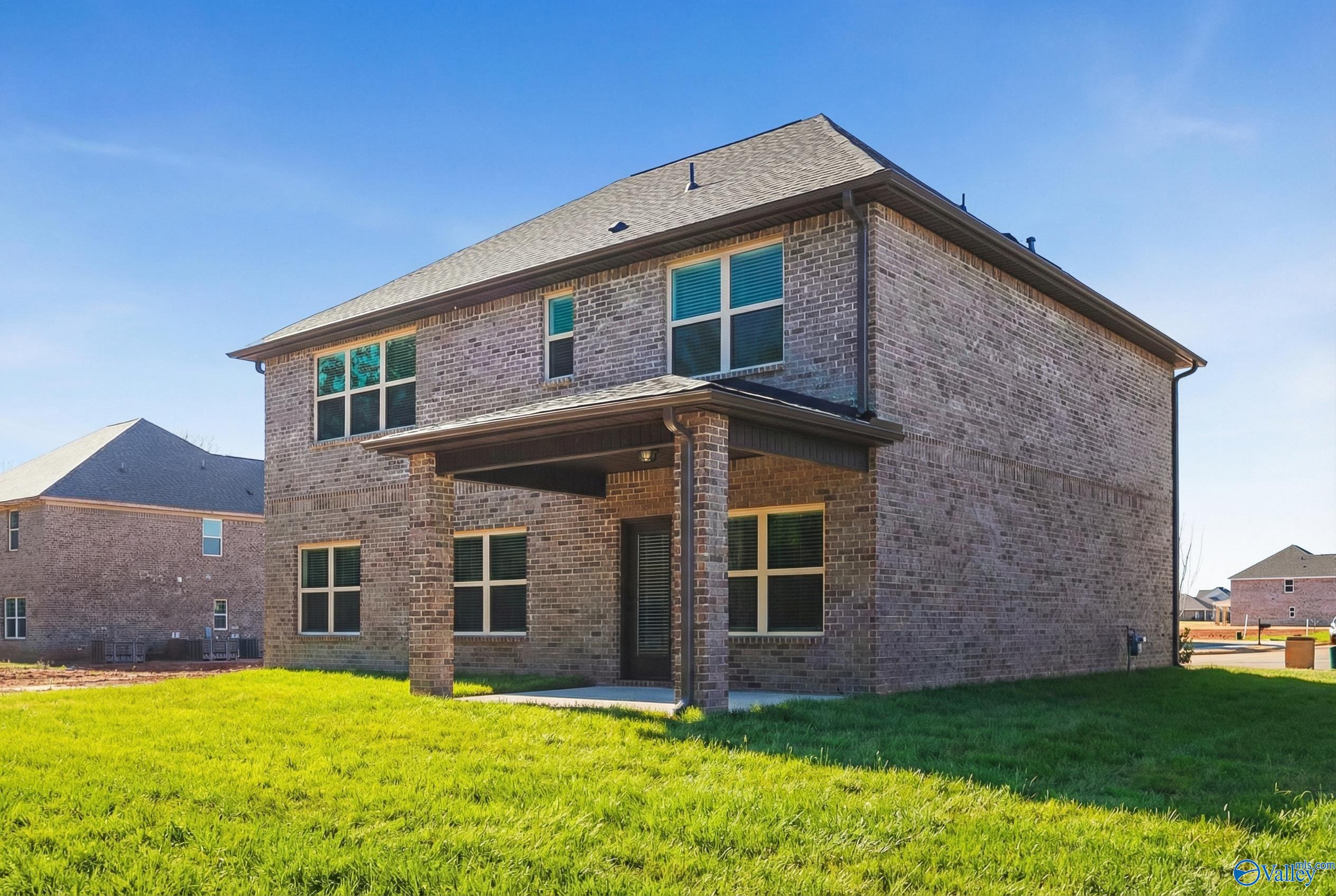 Two-story brick home with covered front porch, large windows, and green lawn in Ricketts Farm, Athens, Alabama by Davidson Homes Shelby A