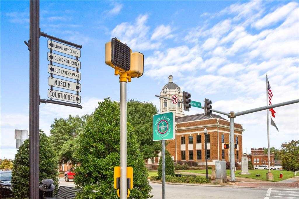 Historic Winder, Georgia courthouse with clock tower, flags, and Cedar Farms community signs at tree-lined intersection