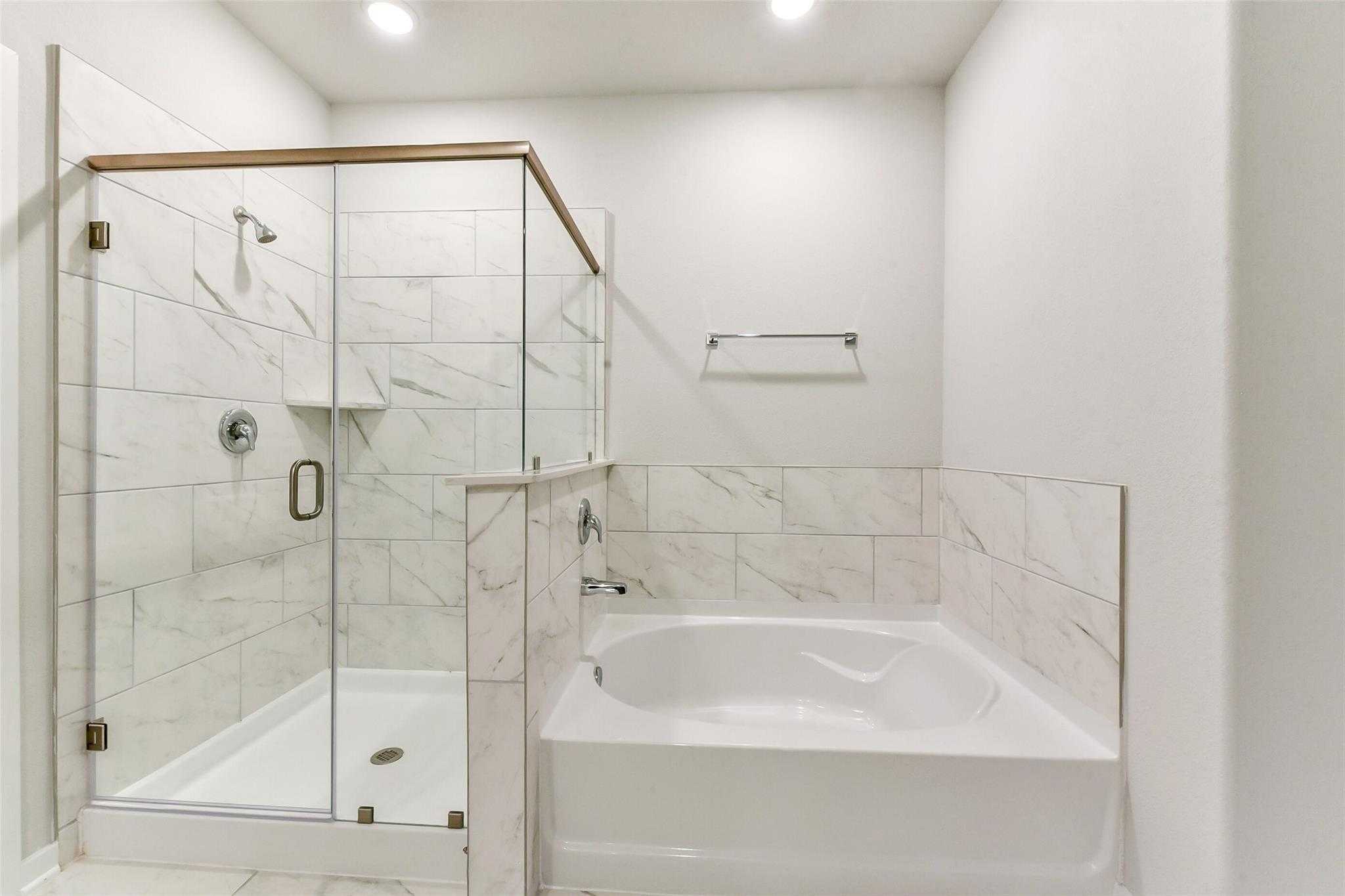 Elegant master bathroom with frameless glass shower, subway tile, and soaking tub in Davidson Homes The Laguna C, Rosharon, Texas