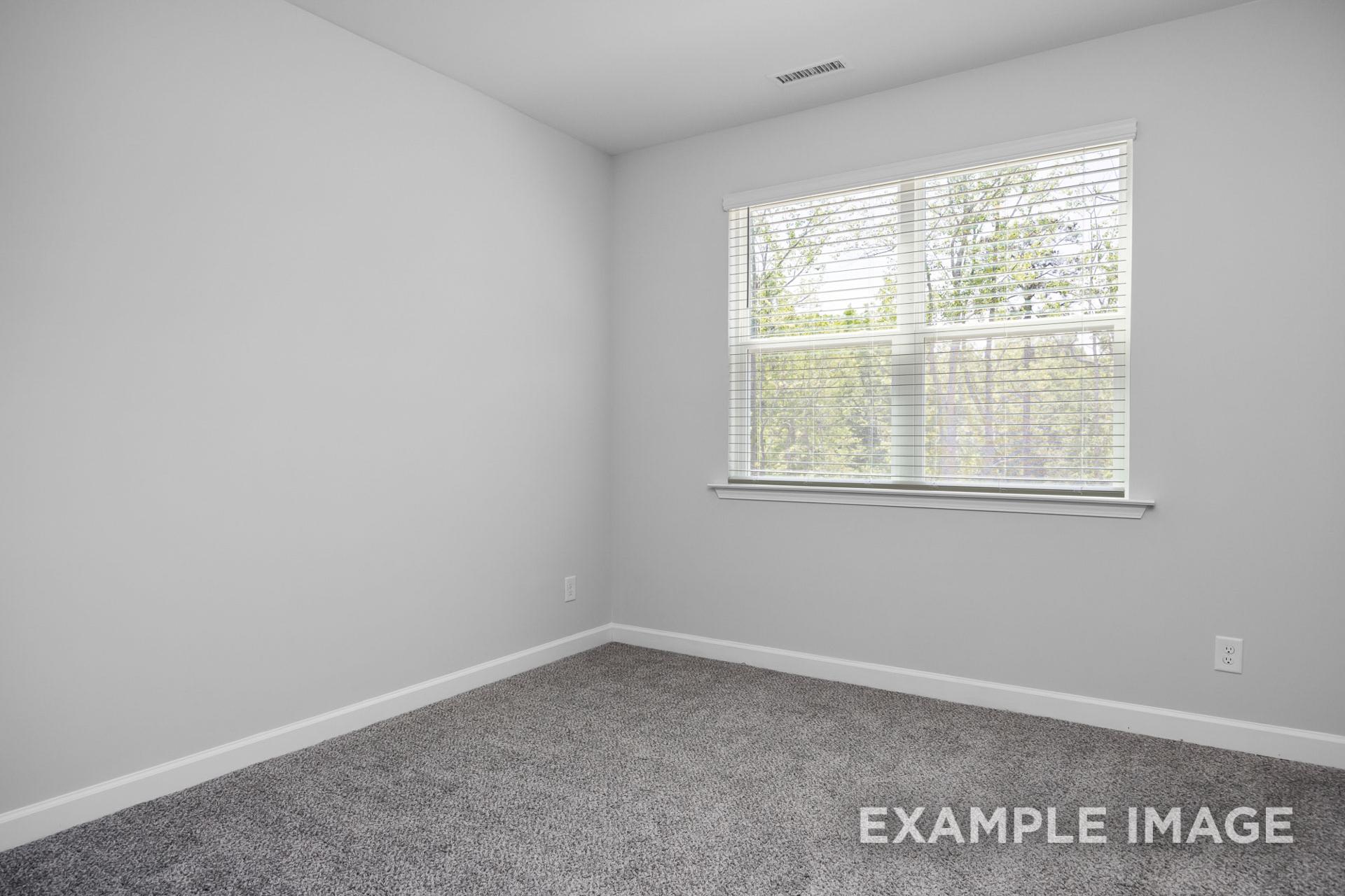 Spacious secondary bedroom in The Preston B with gray walls, carpet flooring, and large windows with blinds