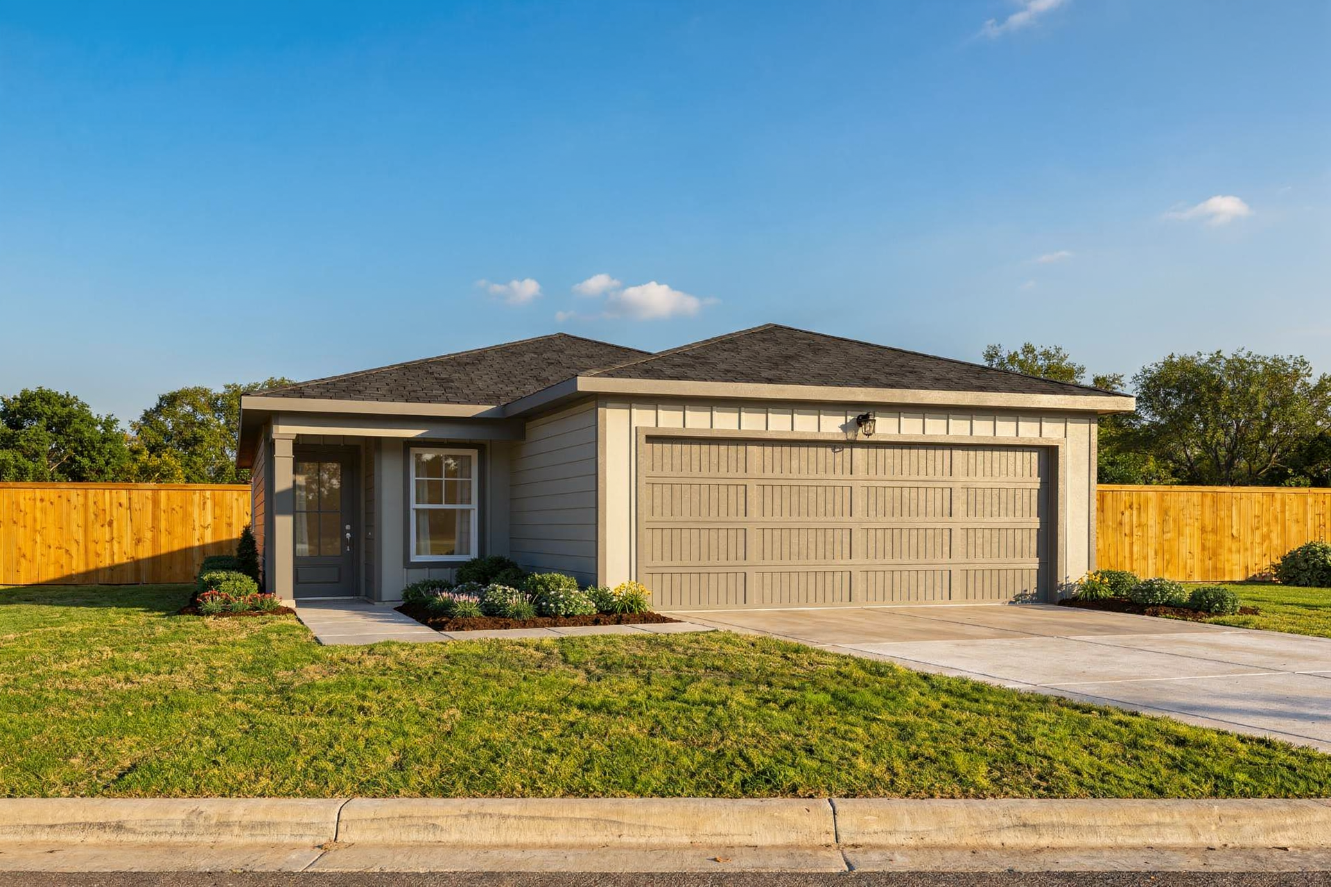 Modern one-story facade of The Colorado home design by Davidson Homes, beige siding, 2-car garage, front porch, lush lawn, San Antonio