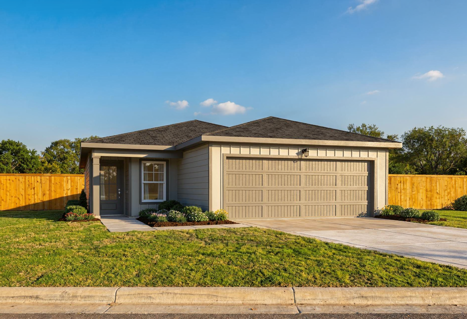 Modern one-story facade of The Colorado home design by Davidson Homes, beige siding, 2-car garage, front porch, lush lawn, San Antonio