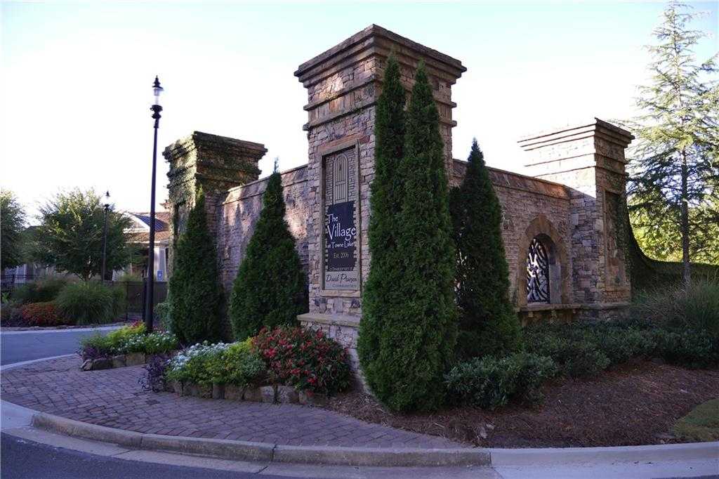 Elegant stone entrance gate to The Village at Towne Lake, Woodstock, Georgia, flanked by tall evergreens and vibrant flowers