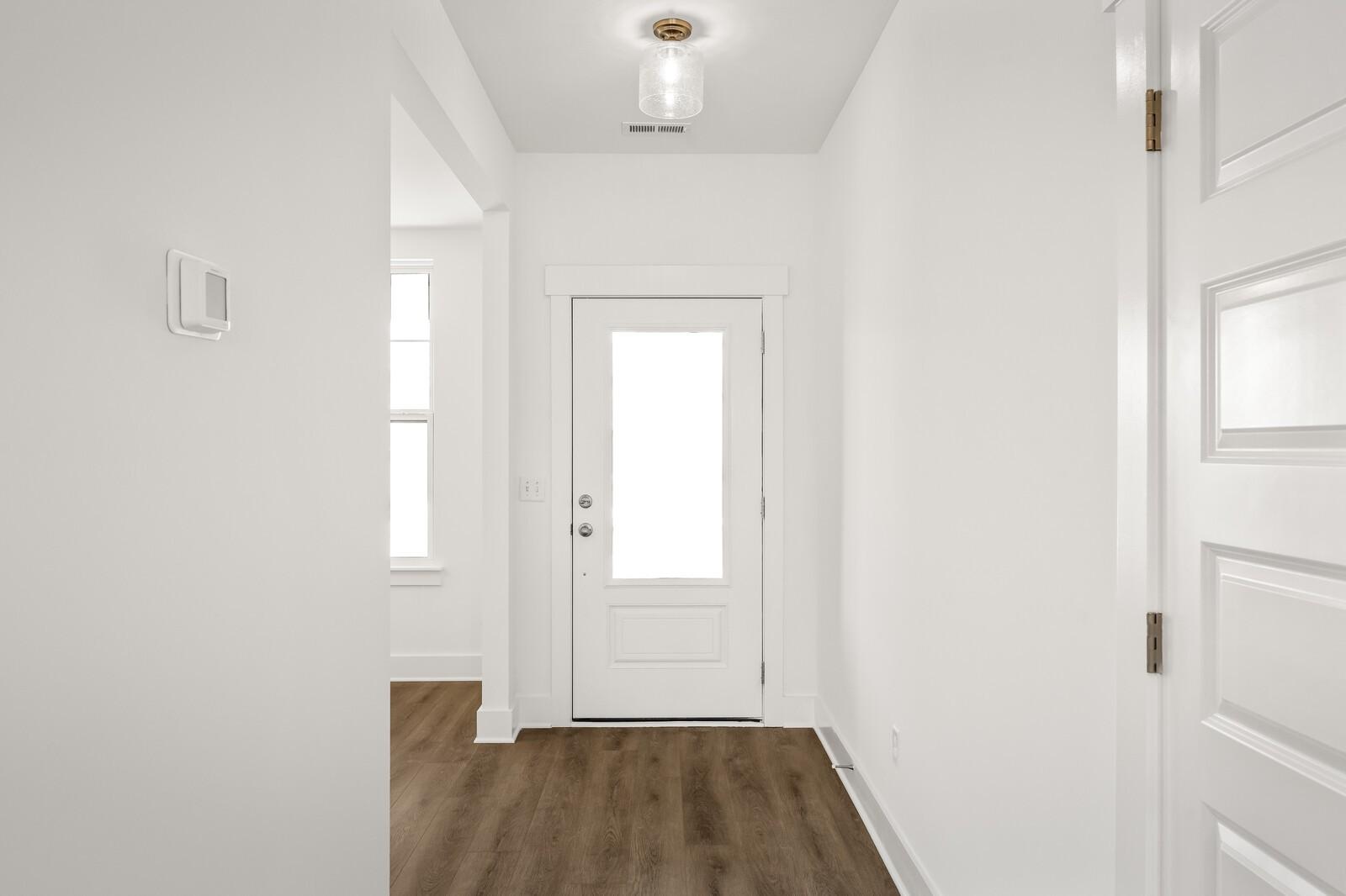 Bright entry hallway with white glass-paneled door, side entry, and hardwood-look flooring in Davidson Homes Willow D, Mt. Juliet, TN