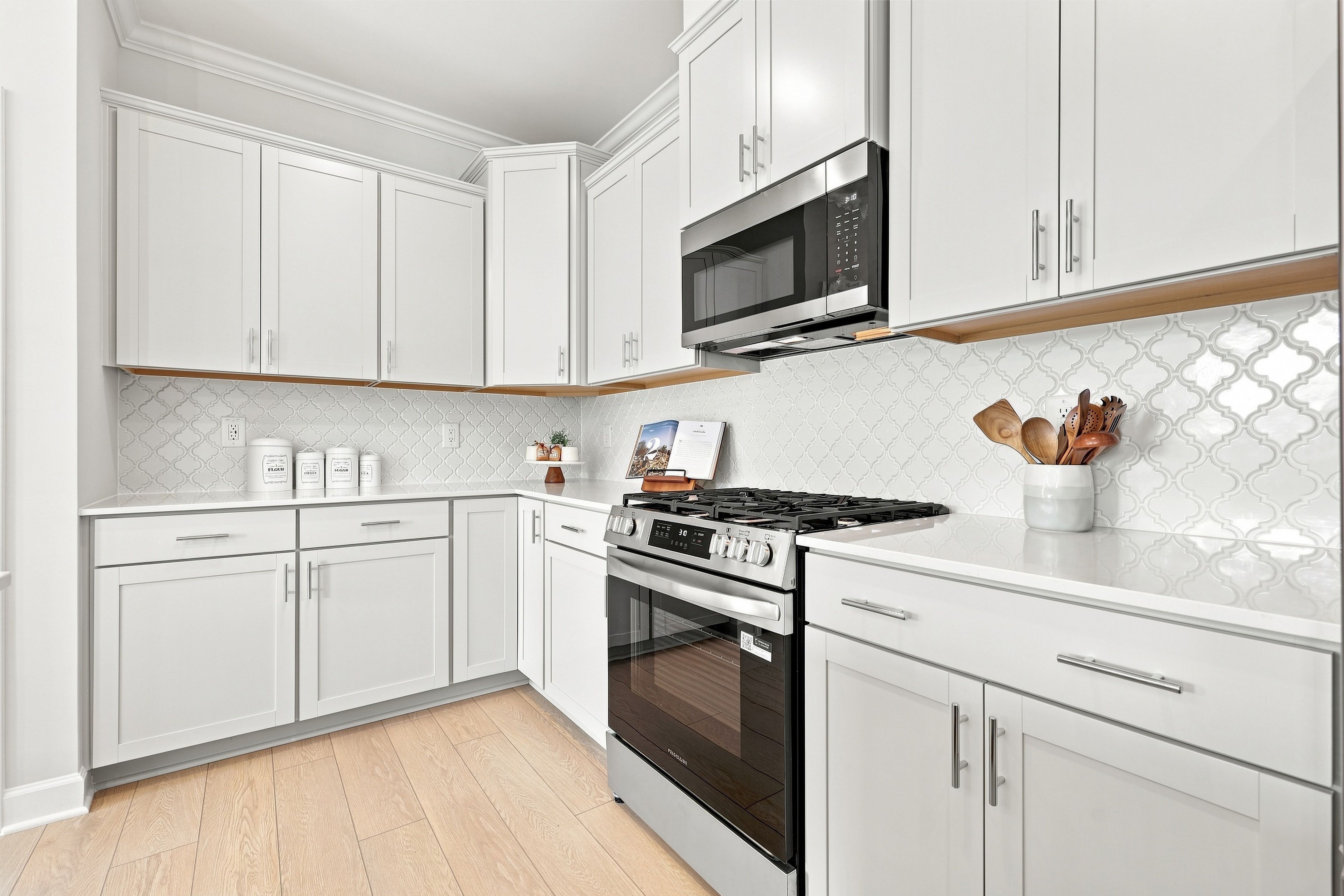 Modern kitchen in The Daphne featuring white shaker cabinets, stainless steel appliances, and elegant arabesque tile backsplash.