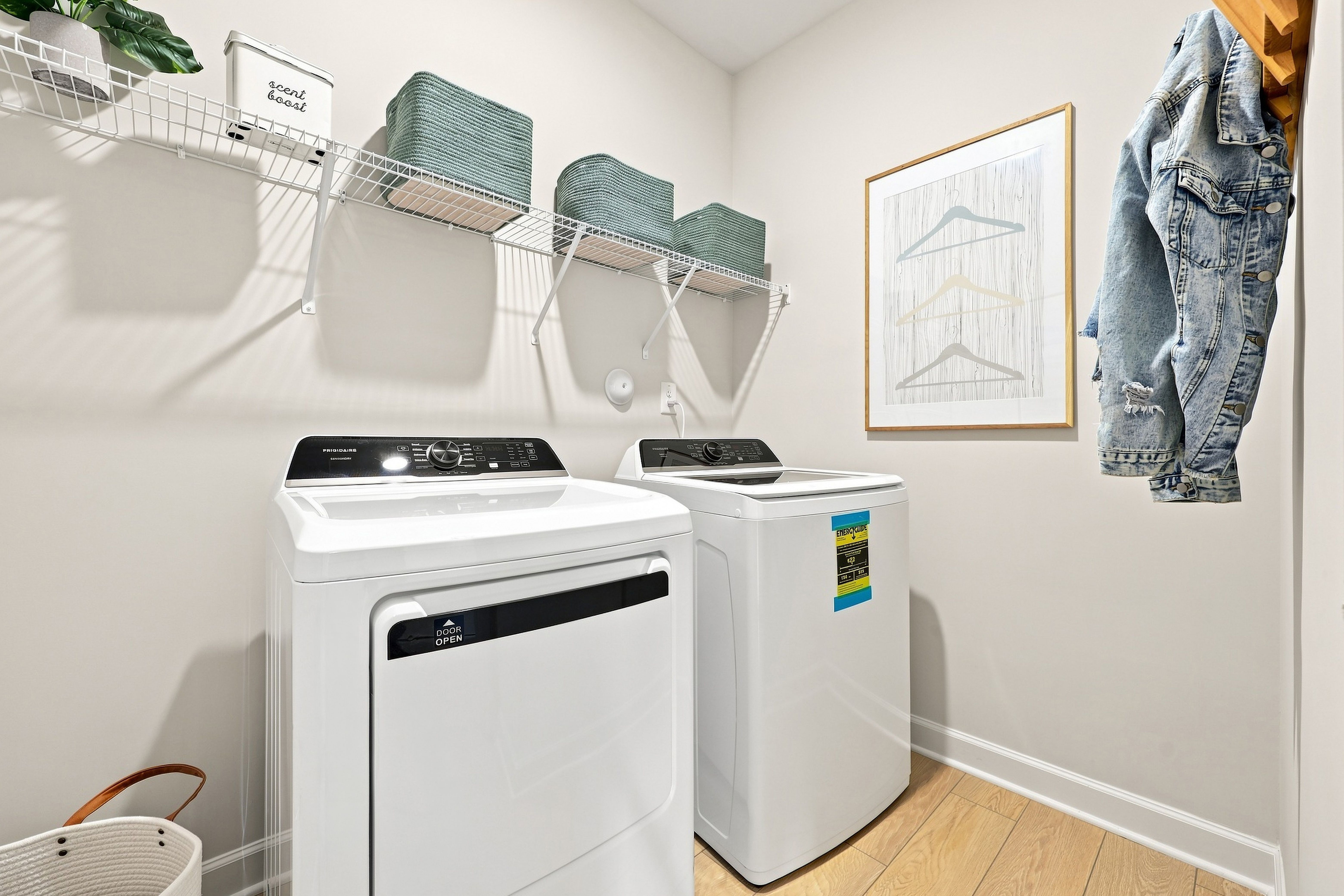 Modern laundry room in The Daphne home design featuring organized wire shelving, storage baskets, and high-efficiency appliances.