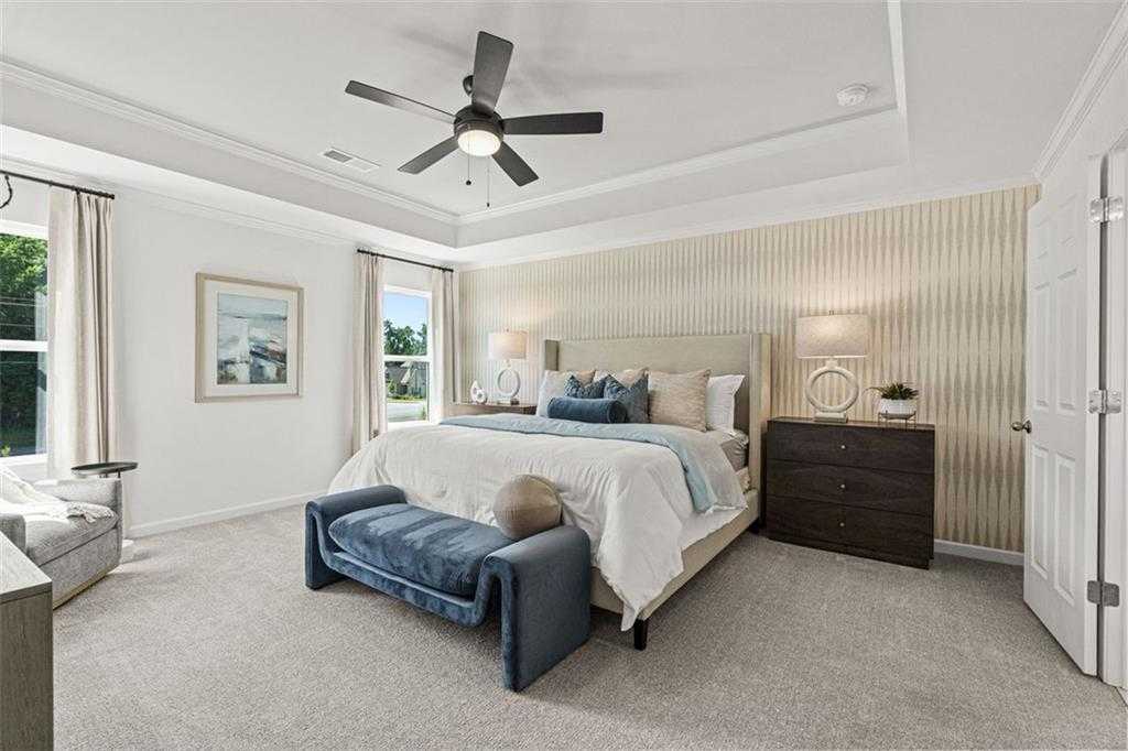 Luxurious master bedroom with king bed, tray ceiling, and large windows in Davidson Homes Hickory B, Hoschton, GA