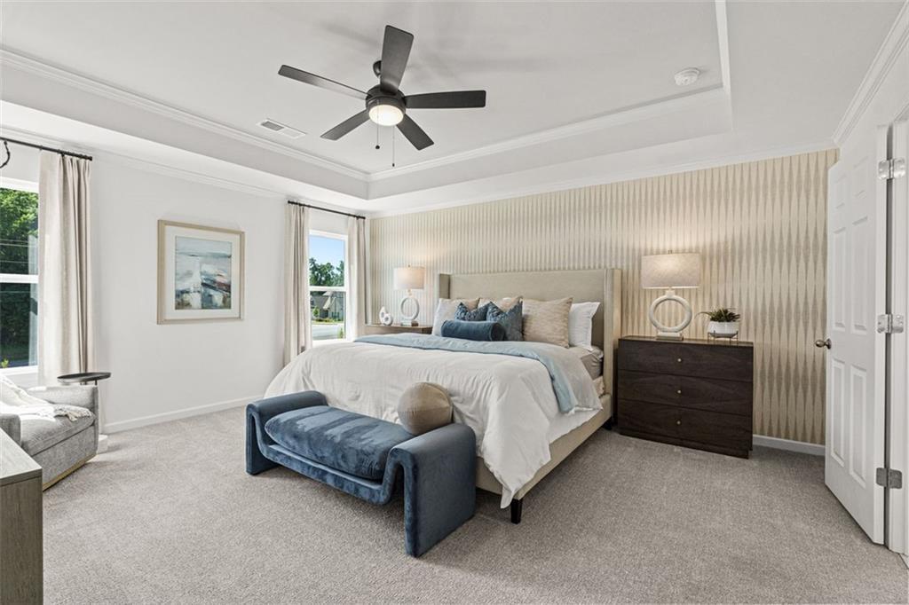 Luxurious master bedroom with king bed, tray ceiling, and large windows in Davidson Homes Hickory B, Hoschton, GA