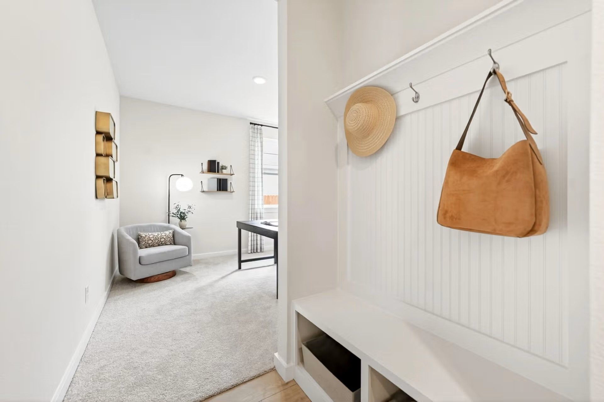 White mudroom bench with coat hooks leading into a bright home office in The Laurel I floor plan by Davidson Homes.