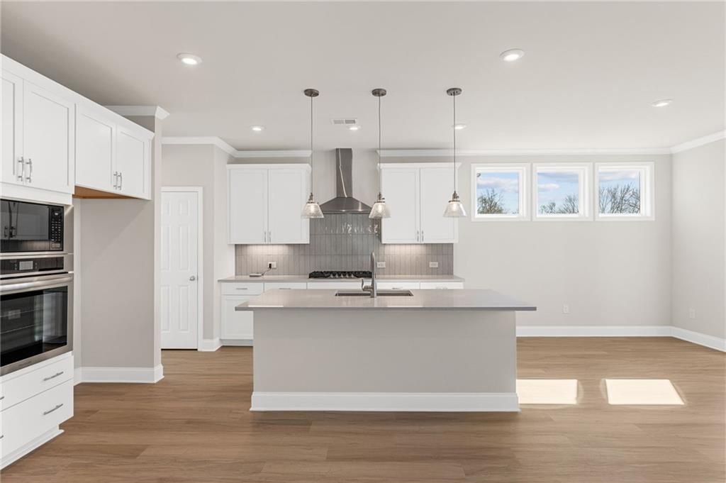 Spacious modern kitchen with white cabinets, quartz island sink, stainless oven in Davidson Homes Willow B, Hoschton GA