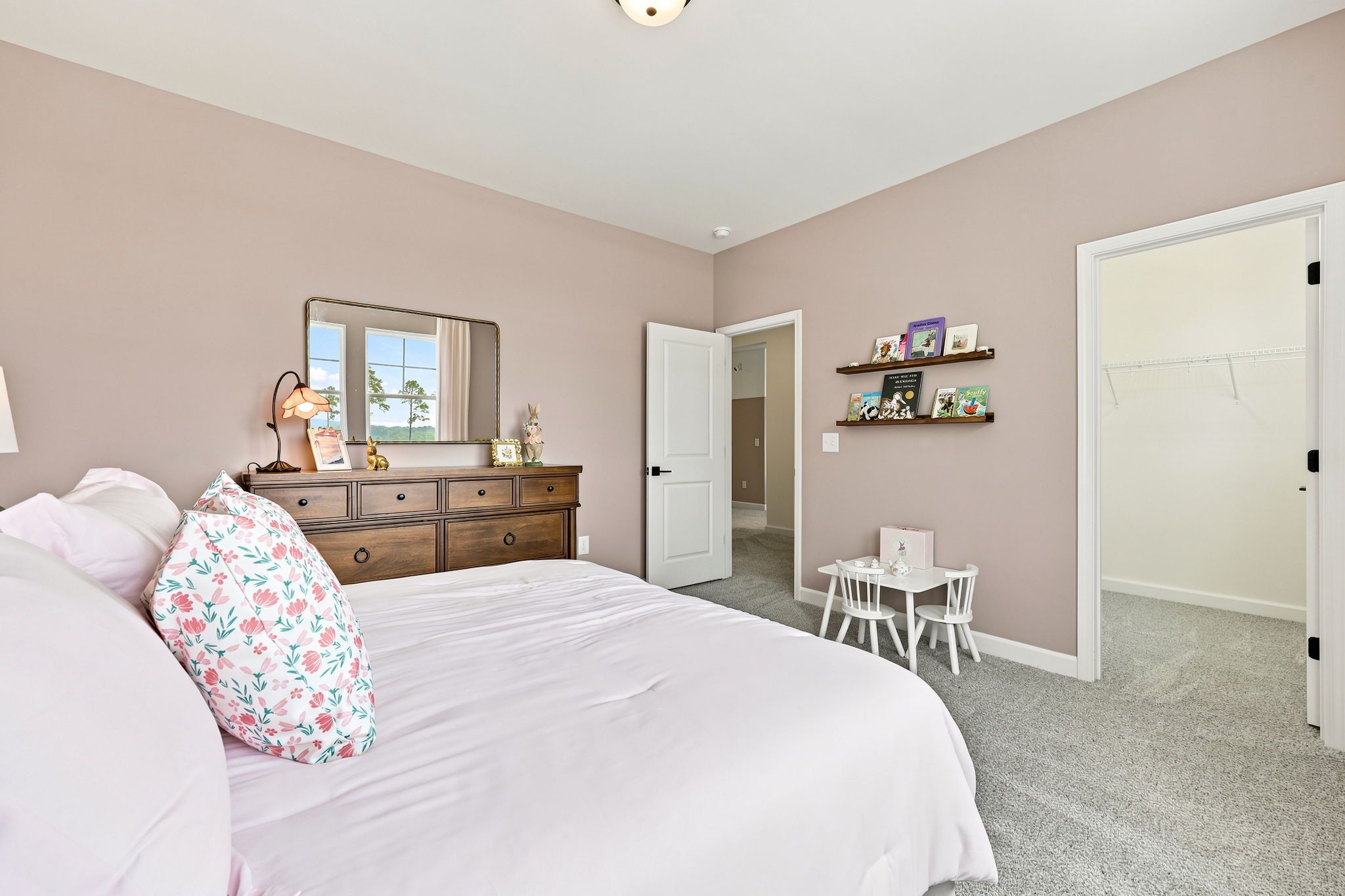Cozy bedroom at Montrose in Aberdeen, NC by Davidson Homes with a dresser, walk-in closet, and children's play area.