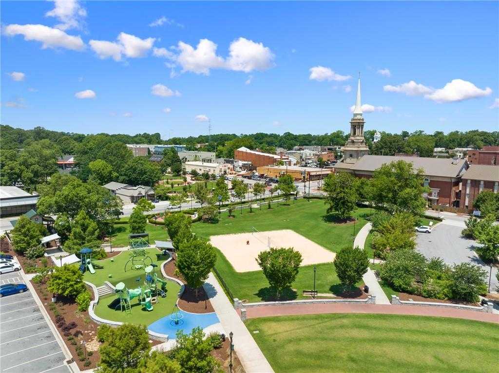 Aerial view of Kelly Preserve park with colorful playground, sand volleyball court, walking paths, and lush trees in Loganville, Georgia