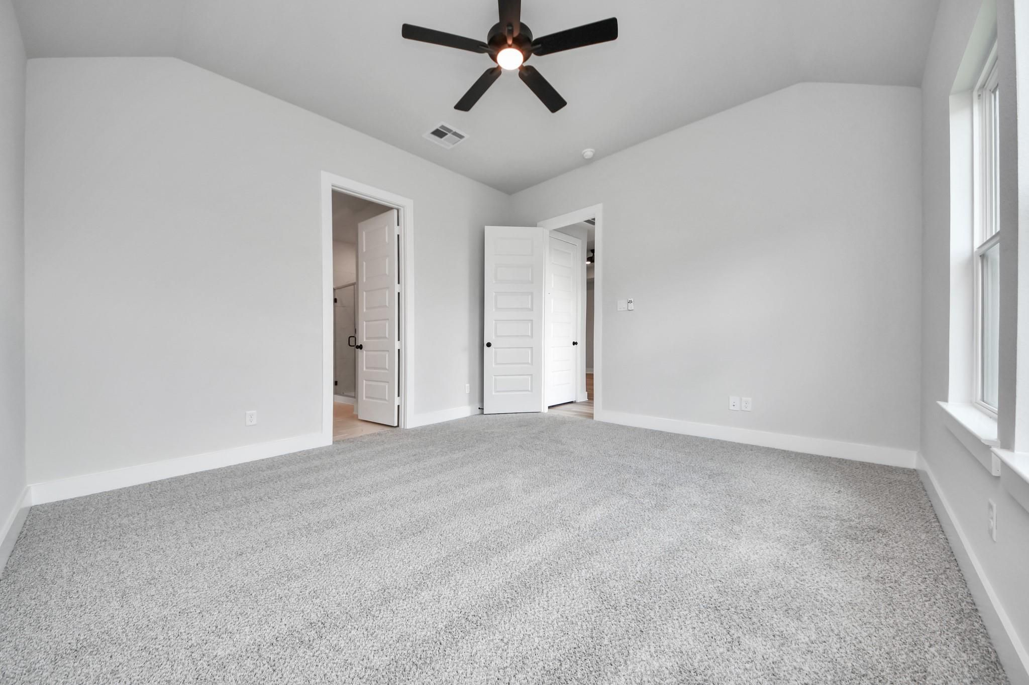Bright, spacious bedroom with neutral carpet and ceiling fan in The Laguna C floor plan by Davidson Homes in Sunterra.