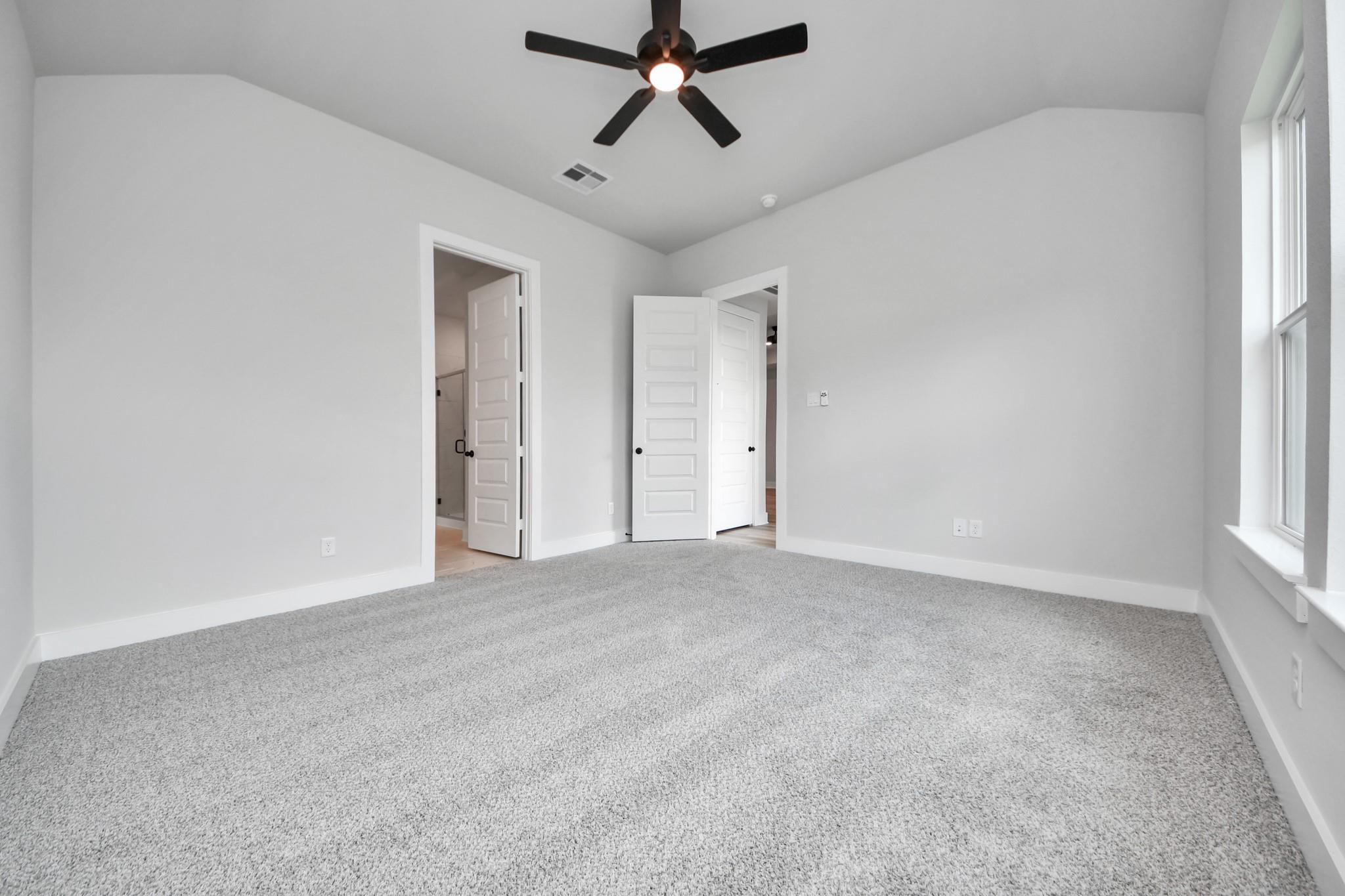 Bright, spacious bedroom with neutral carpet and ceiling fan in The Laguna C floor plan by Davidson Homes in Sunterra.