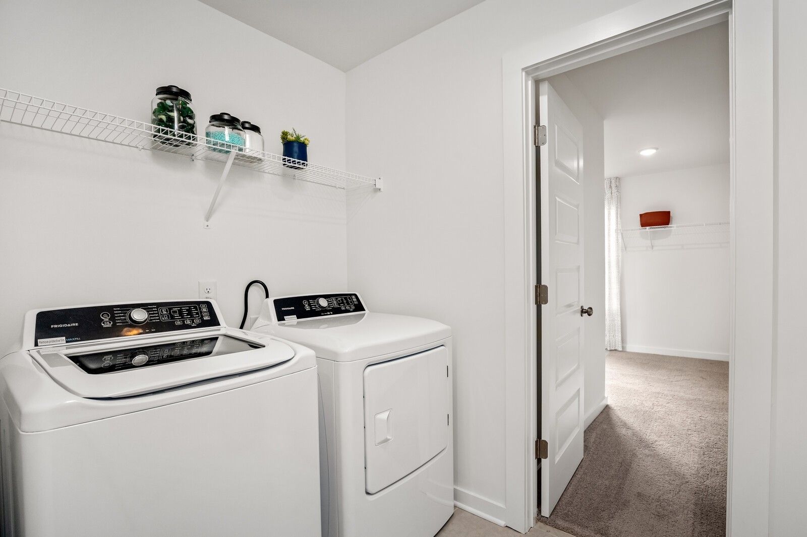 Spacious laundry room featuring Frigidaire washer, dryer and wire shelving in Davidson Homes The Gordon C, Sage Farms, White House, TN