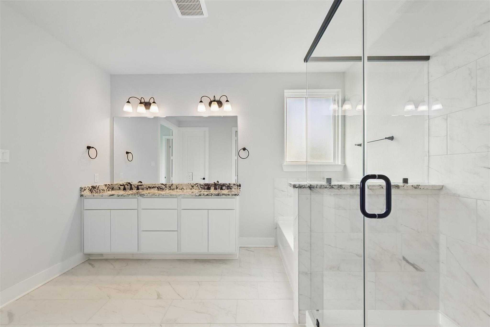 Elegant master bathroom with double vanity, frameless glass shower, and soaking tub in Davidson Homes The Victoria C, Lago Mar