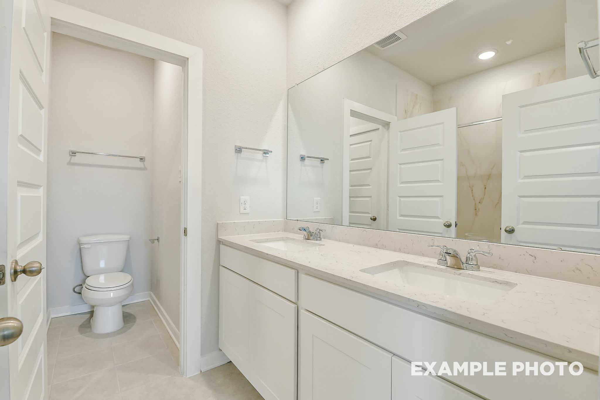 Bright master bathroom in The Colorado by Davidson Homes featuring dual vanity, quartz countertops, and separate water closet