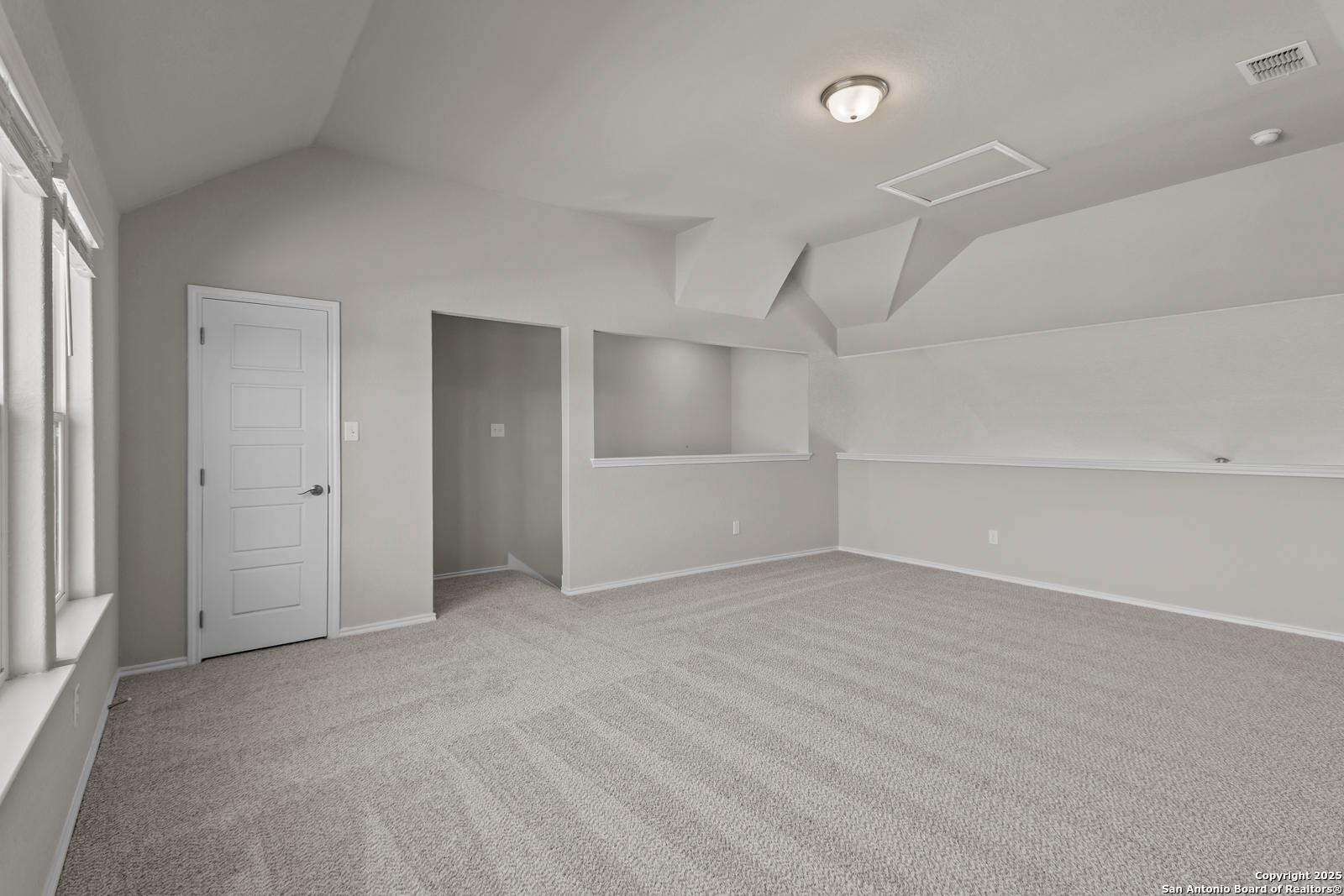 Spacious bedroom with vaulted ceiling, built-in shelves, and carpet in Davidson Homes The Collin B, Seguin Texas