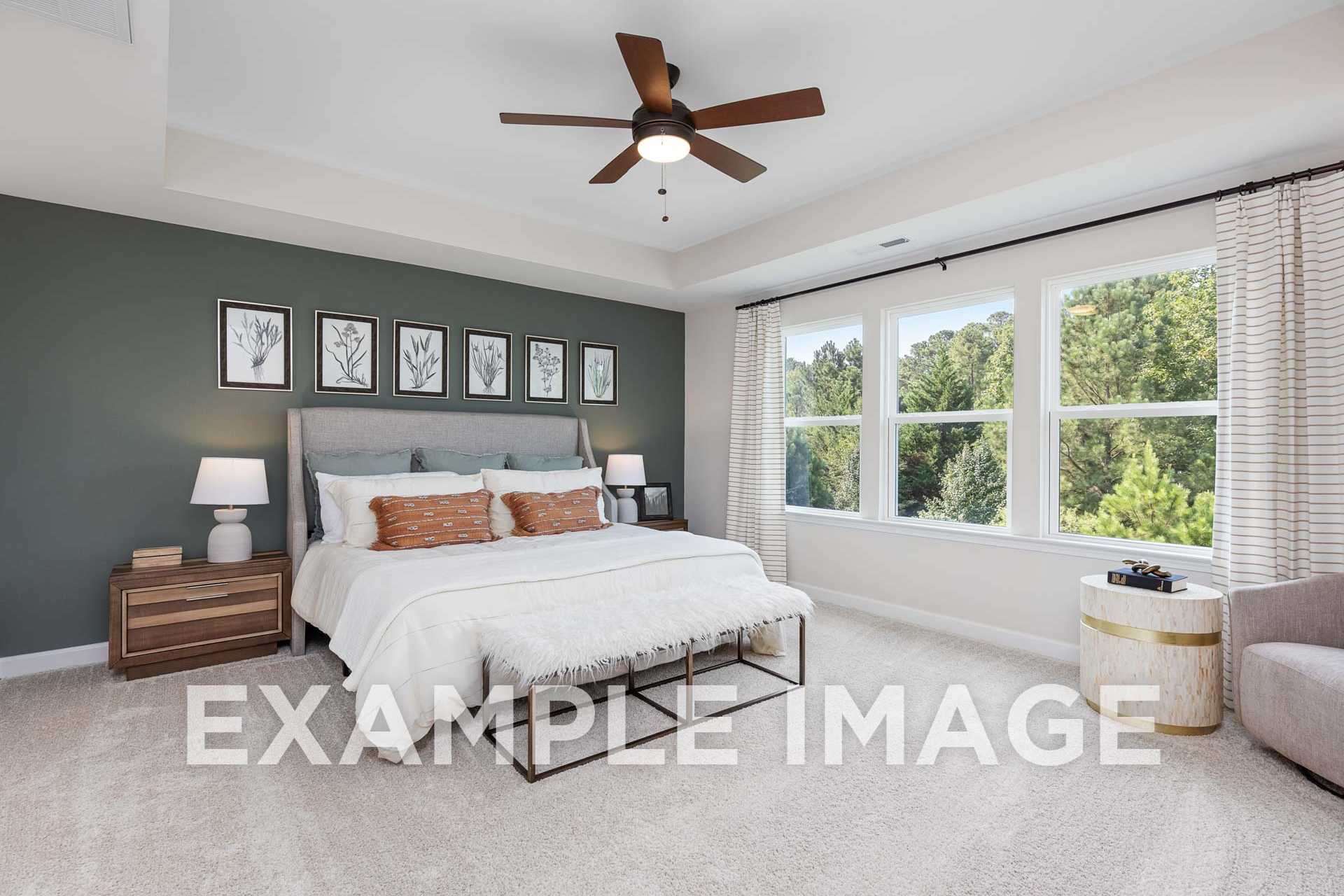Spacious upstairs master suite in The Willow F by Davidson Homes featuring king bed, gray accent wall with botanical art, and wooded window views