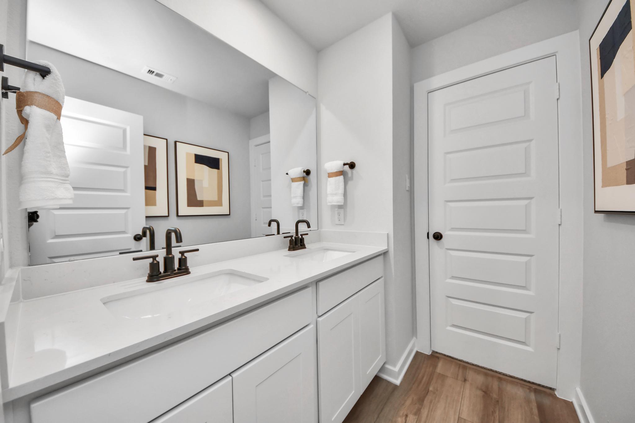 Modern double vanity bathroom at Robins Landing in Houston, TX by Davidson Homes with white quartz countertops.