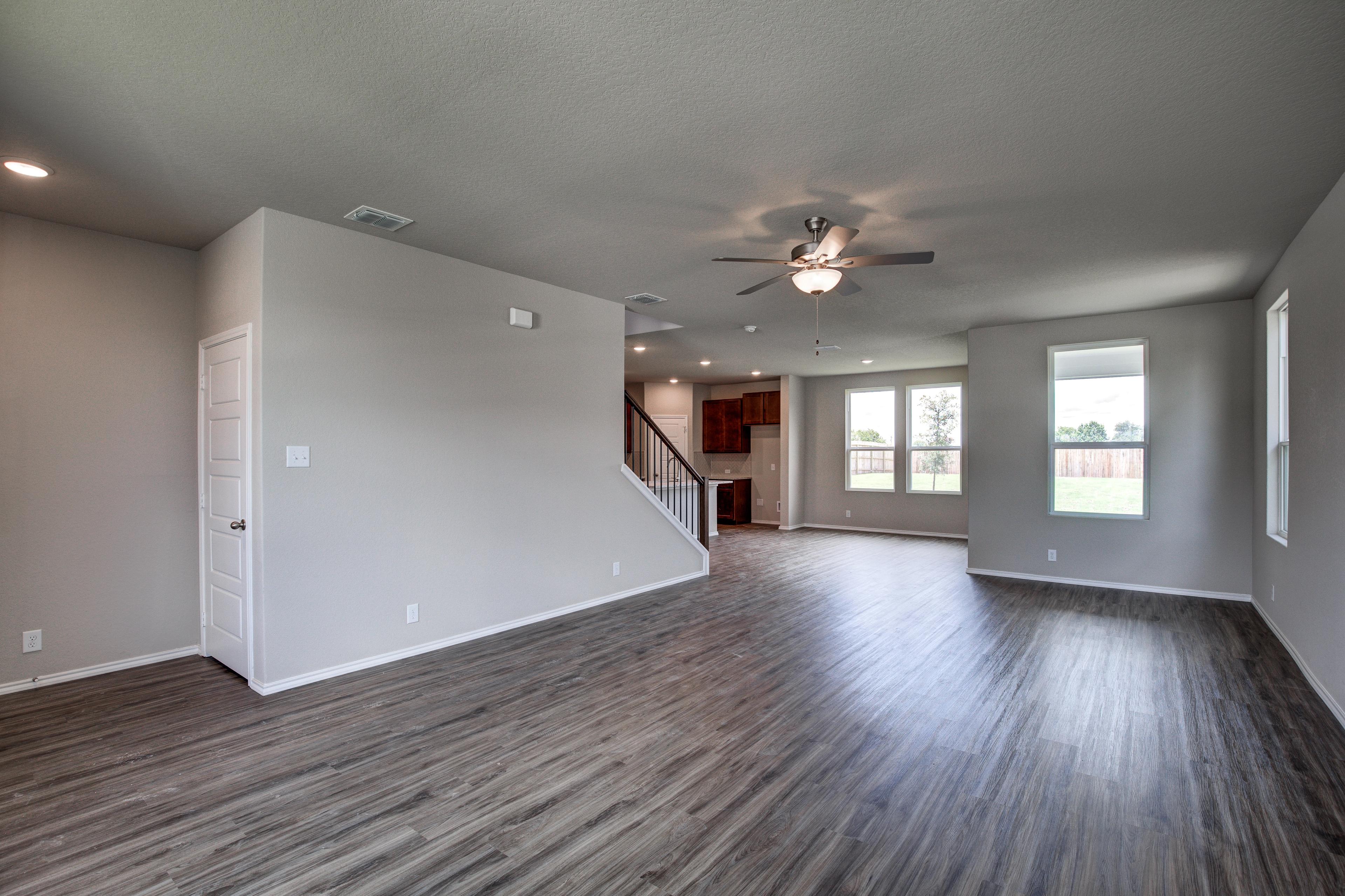 Spacious open-concept great room in The Murray G with hardwood floors, ceiling fans, staircase, and large windows