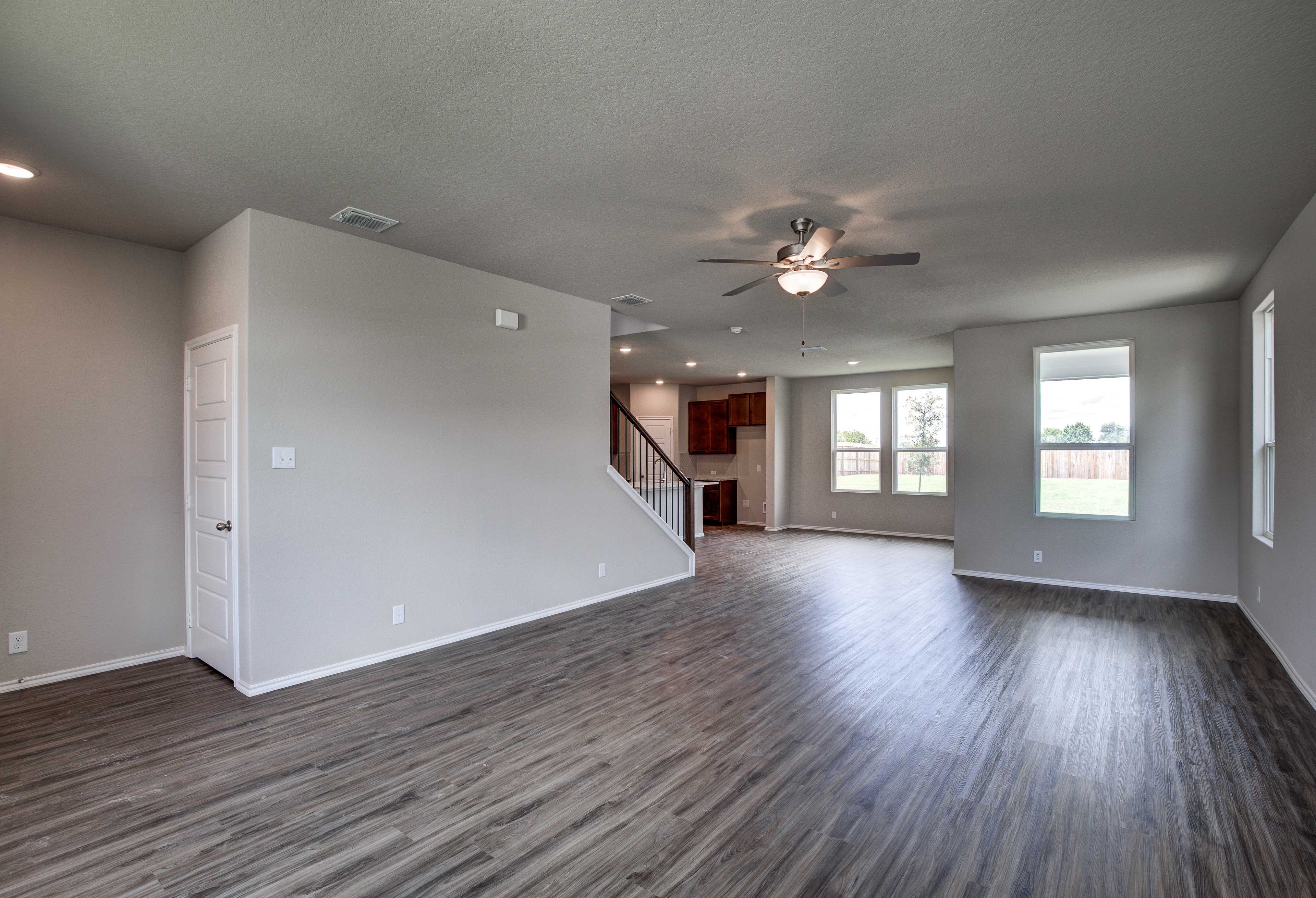 Spacious open-concept living room in The Murray with hardwood floors, ceiling fan, staircase, and large windows