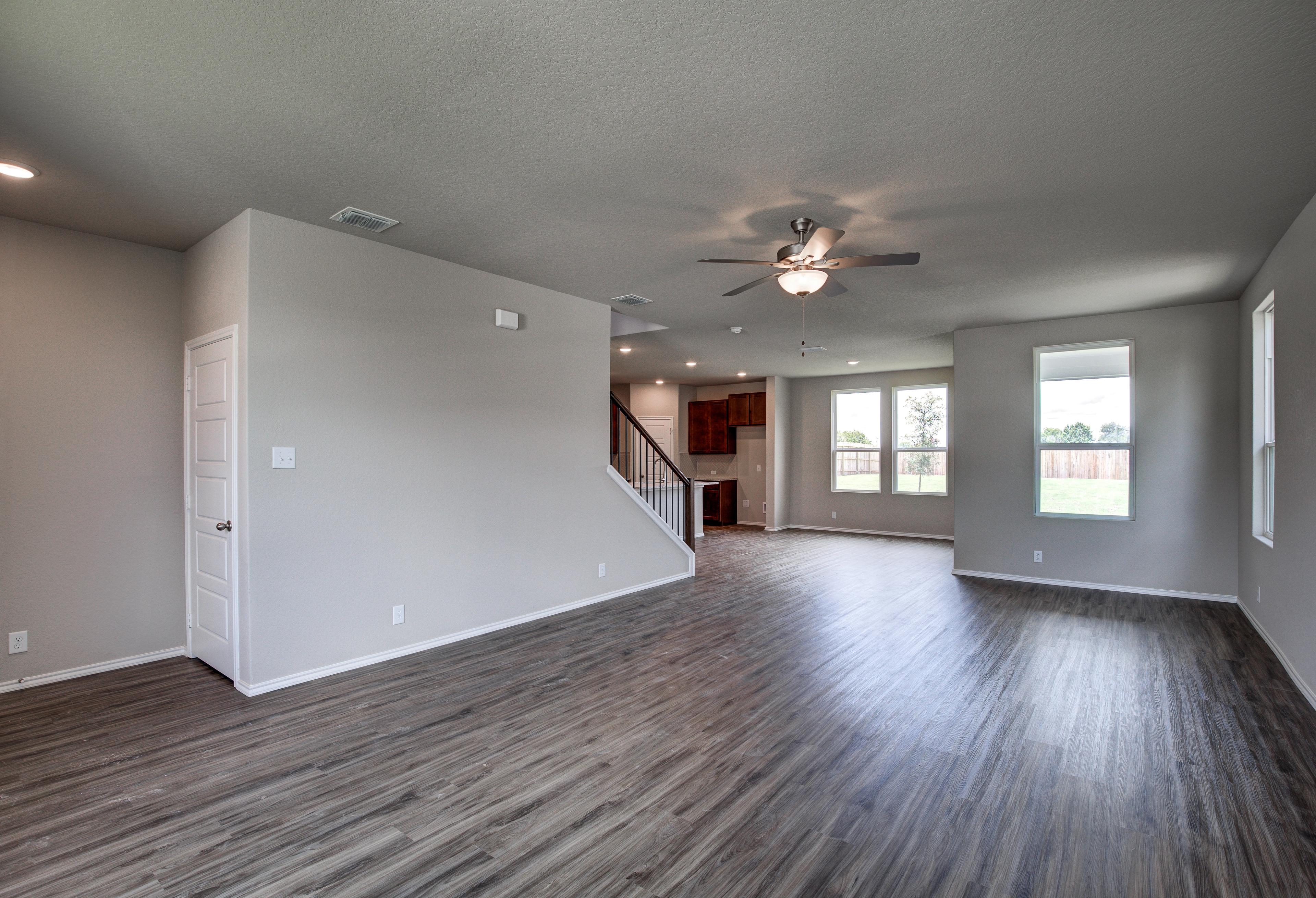 Spacious open-concept living room in The Murray featuring hardwood floors, ceiling fans, large windows, and staircase