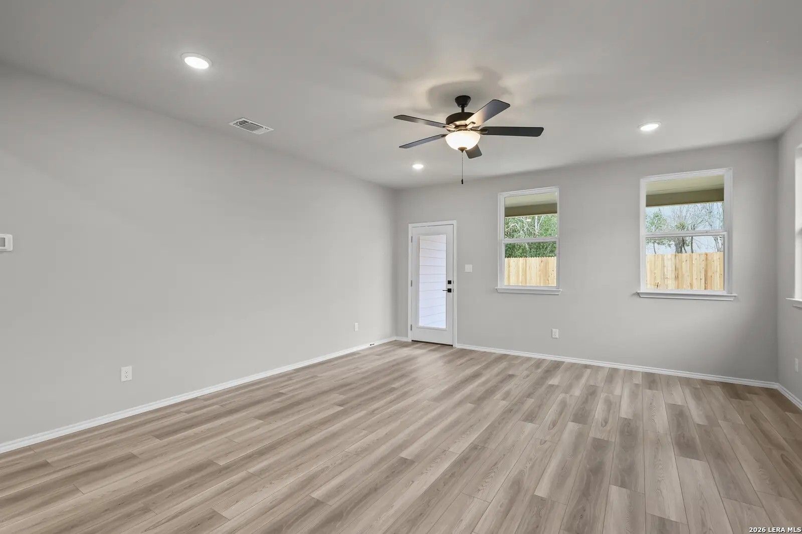 Spacious living room with wood-look flooring and ceiling fan in The Glenwood E floor plan at Comanche Ridge, San Antonio.