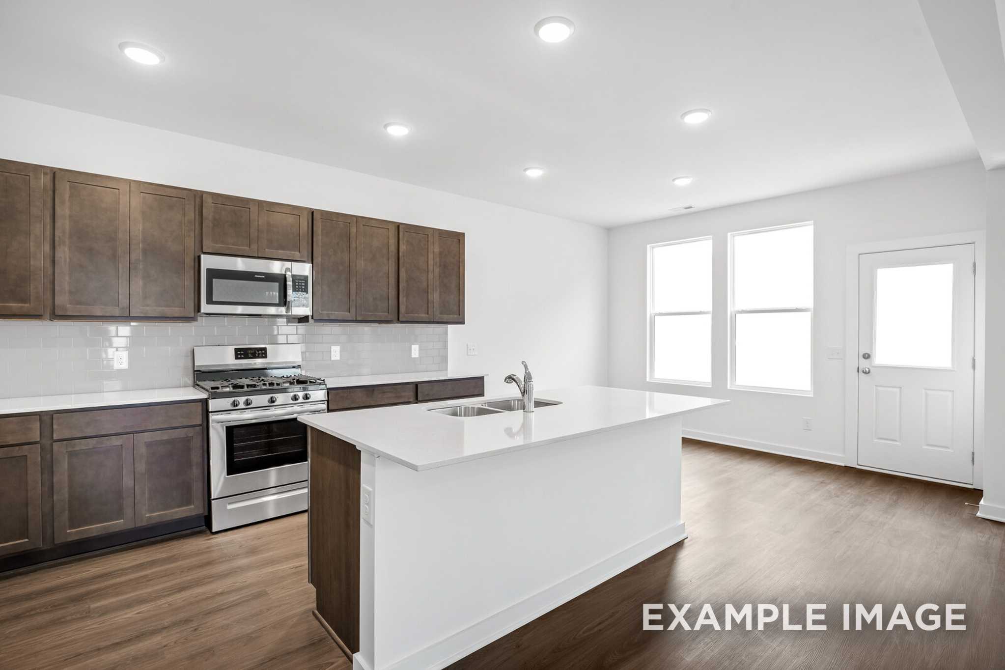 Modern Grayson C kitchen with brown shaker cabinets, stainless steel appliances, white quartz island, subway backsplash, open layout