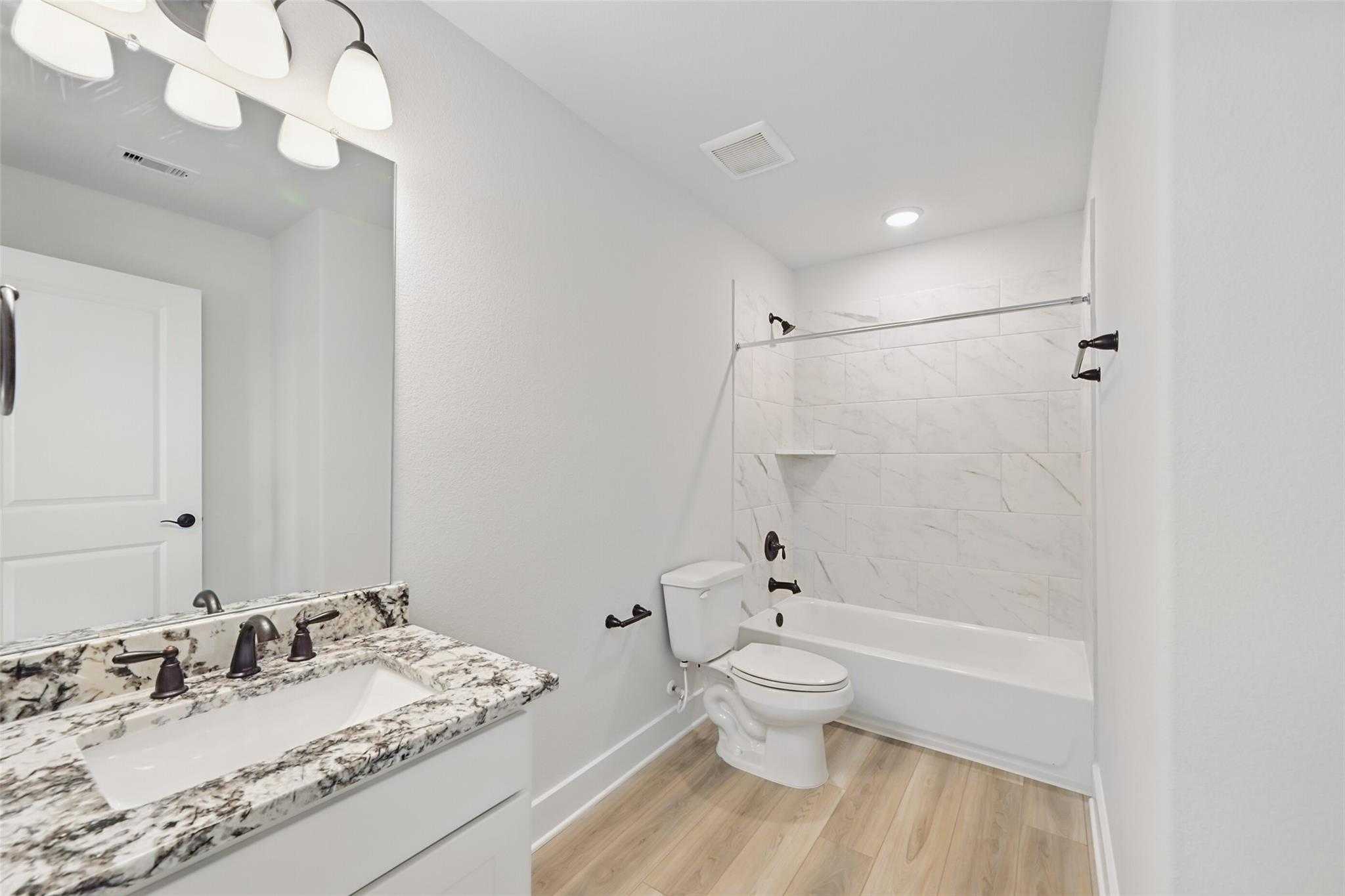 Modern bathroom with marble vanity, white subway tile shower-tub, black fixtures in Davidson Homes The Victoria C, Lago Mar, TX