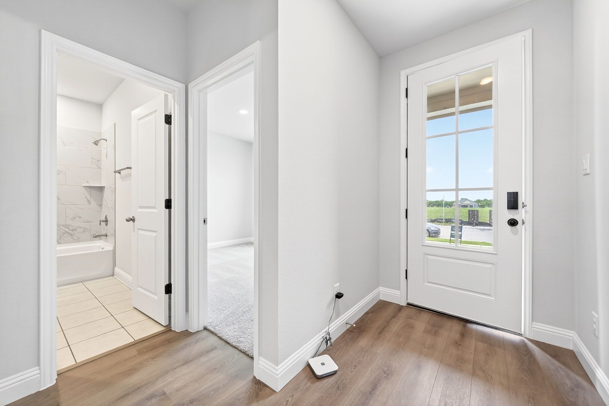 Entryway and interior layout of The Redbud home design featuring wood-look flooring, guest bathroom, and bedroom access.