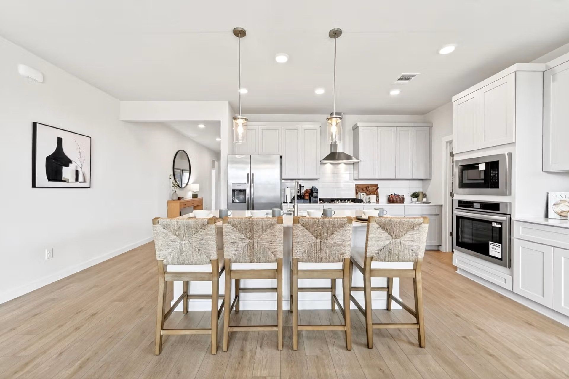 Modern kitchen with island seating, stainless appliances, and white cabinets in The Laurel I floor plan, Heartland, TX.